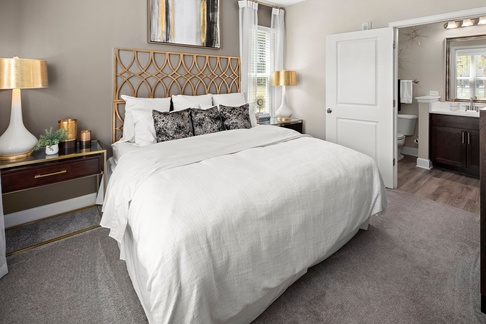Bedroom with bed, nightstands, and doorway to a bathroom. Neutral tones, gold accents.