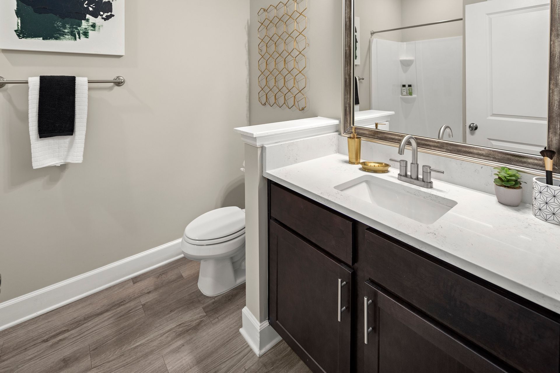 Modern bathroom with dark wood cabinets, white countertop, toilet, and shower.
