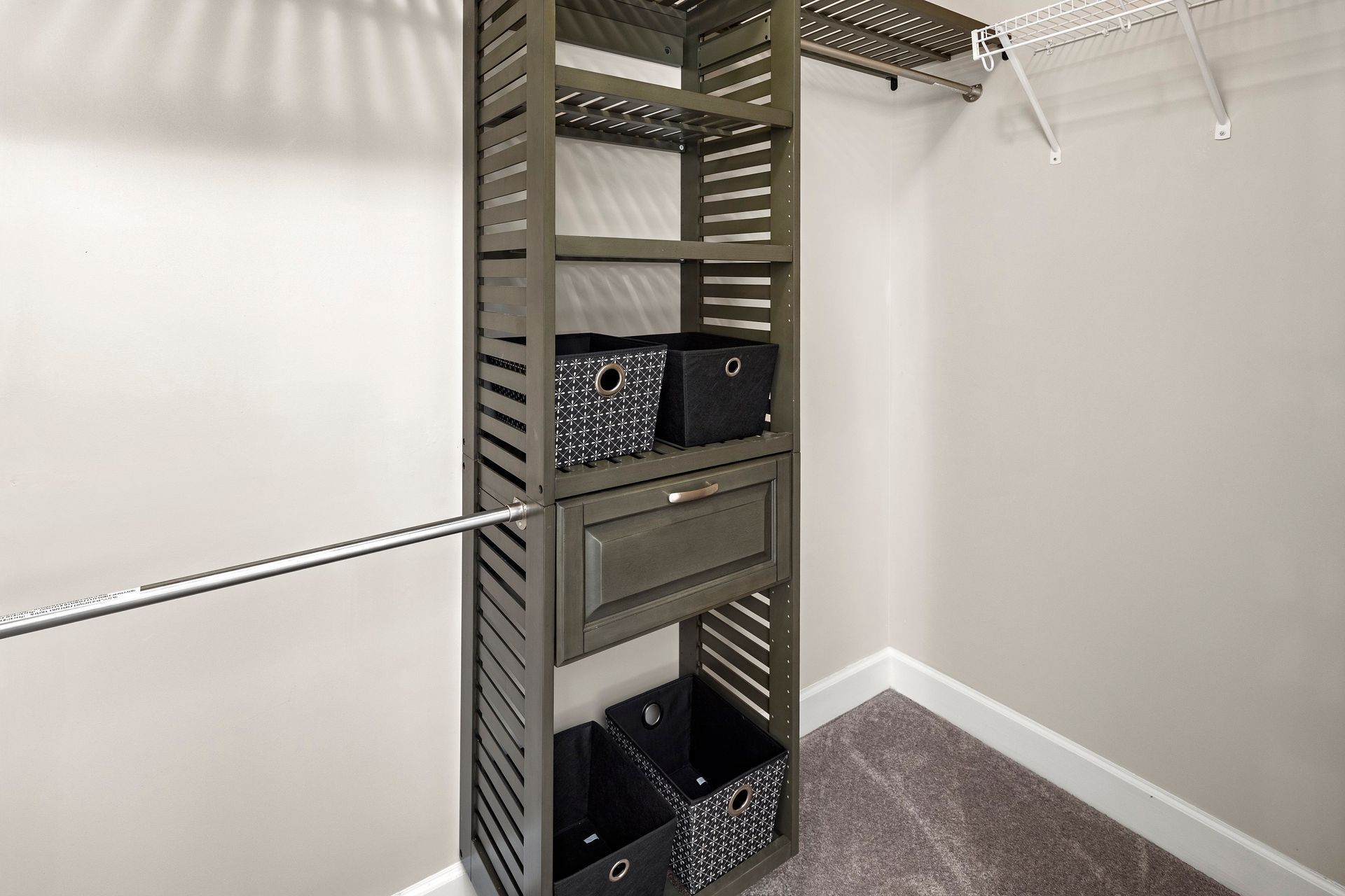 Closet with gray shelving unit, clothes rod, and storage bins.