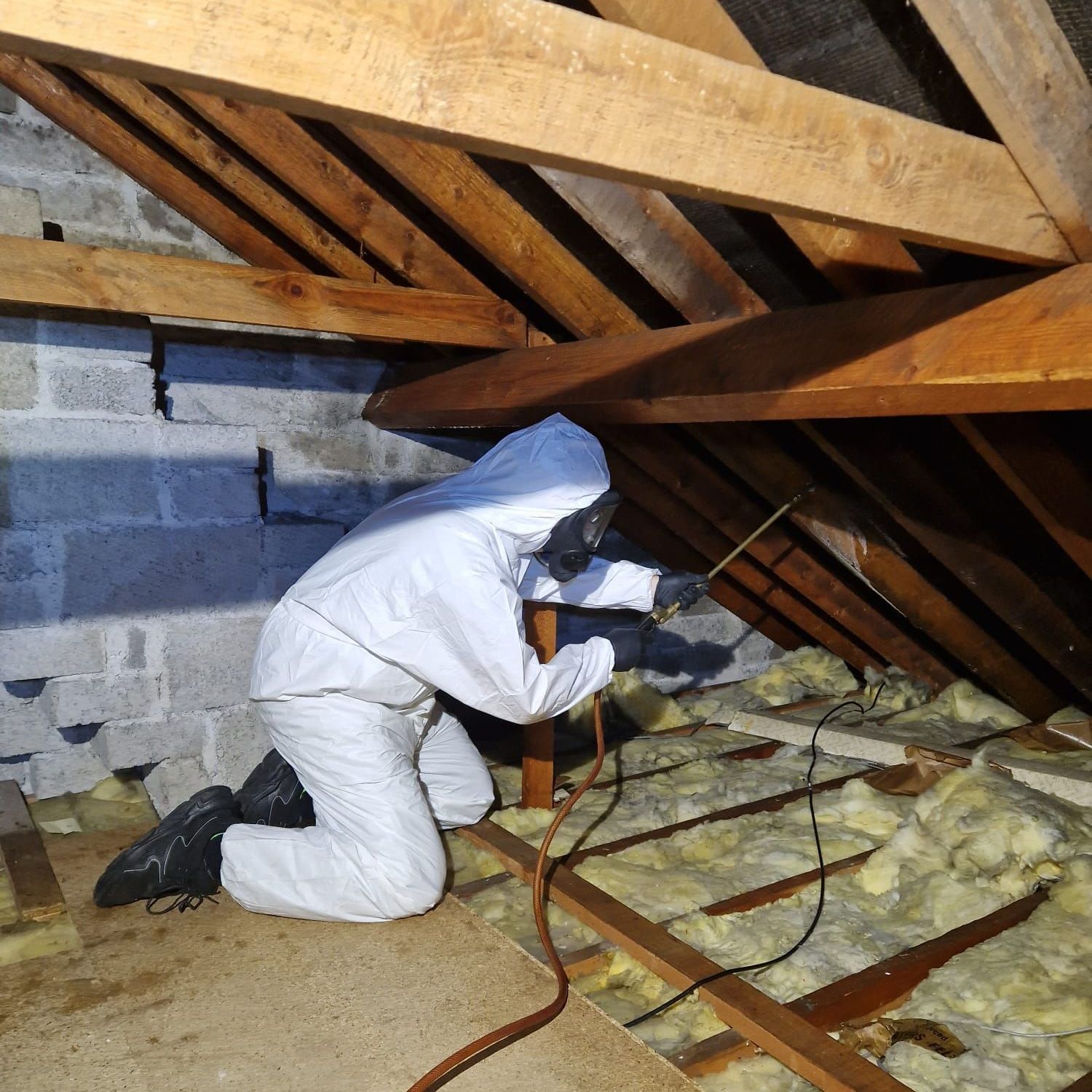 A man in a white suit is kneeling down in an attic