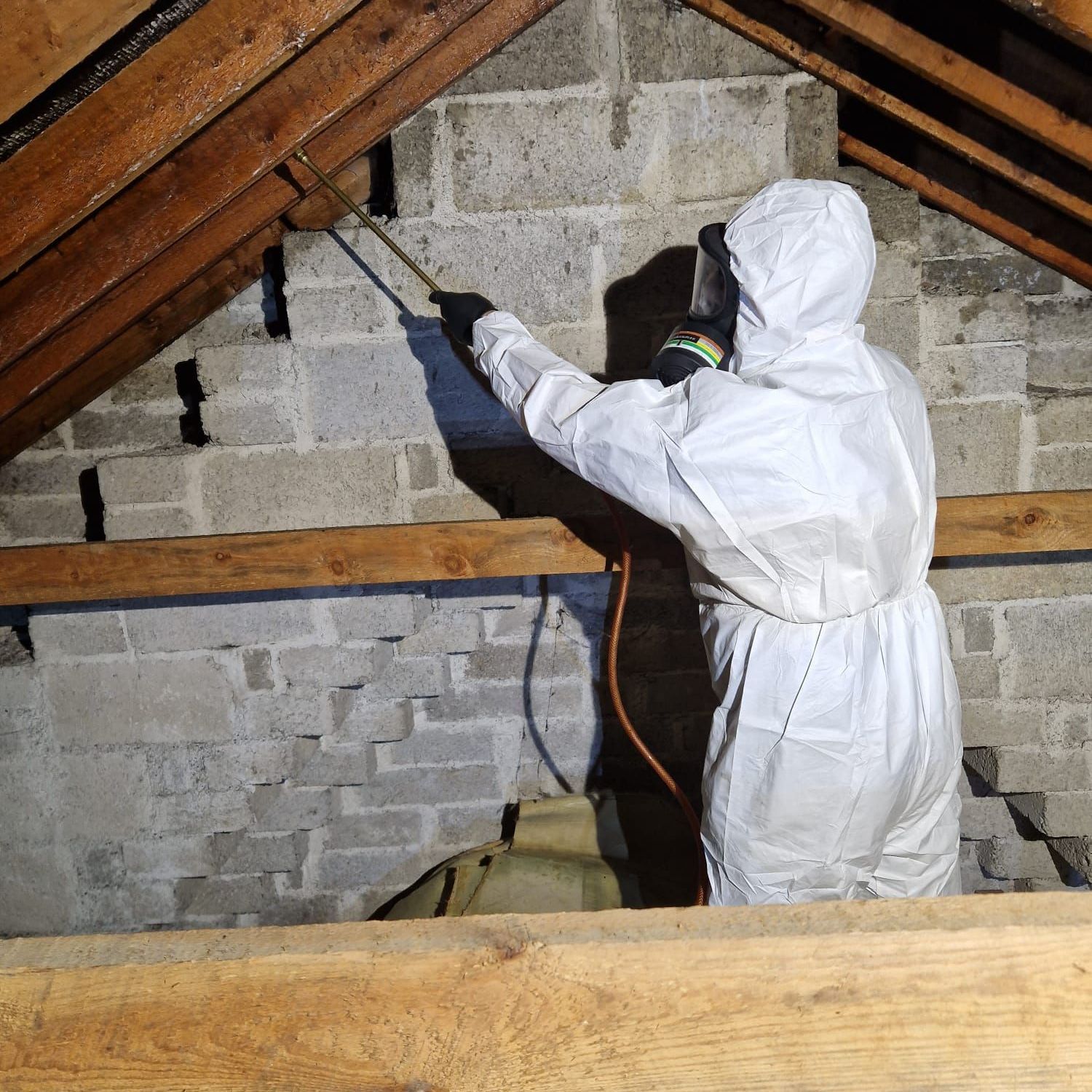 A person spraying a brick wall with a sprayer