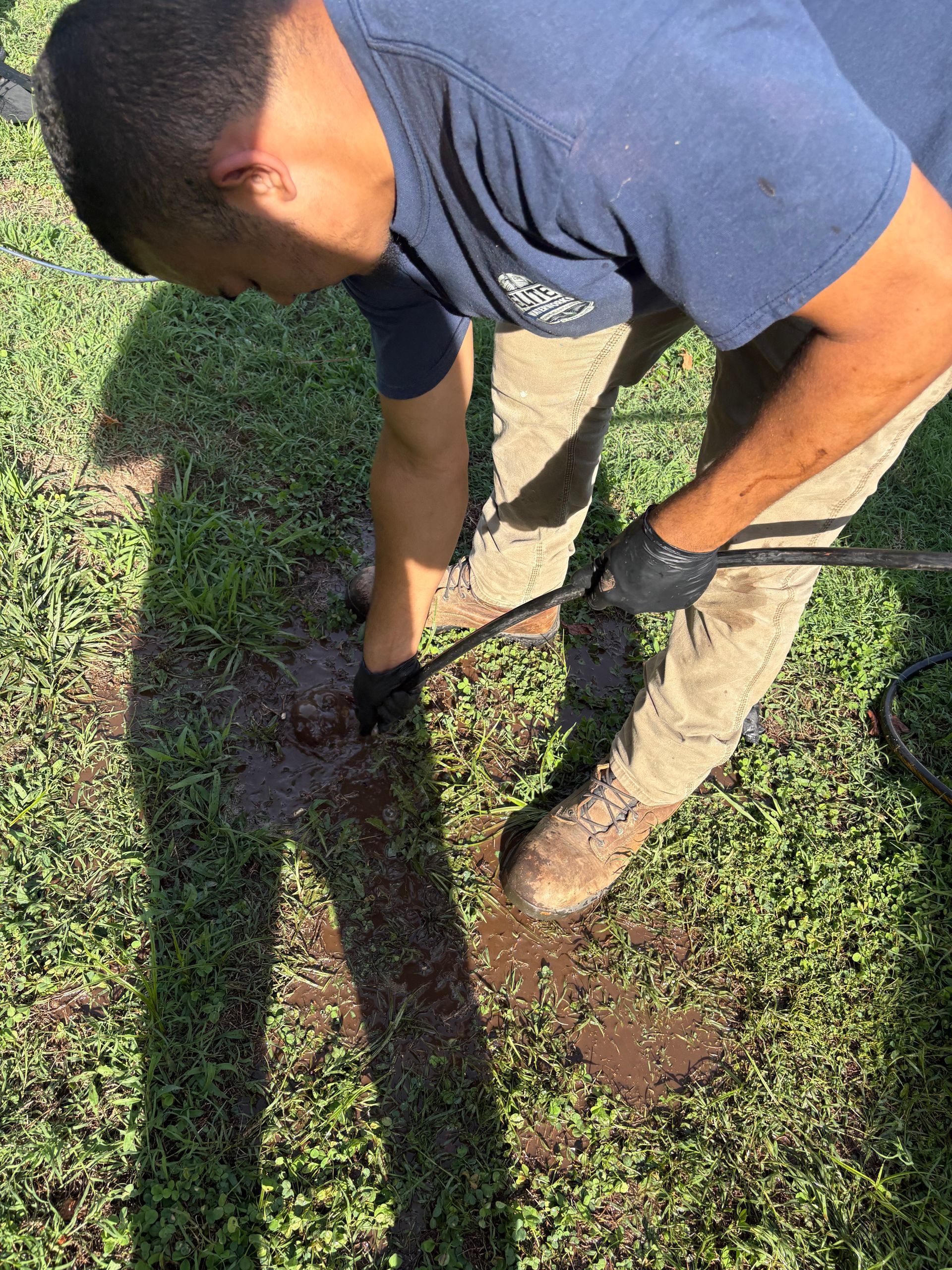 Person using a shovel to dig a hole in a grassy yard.