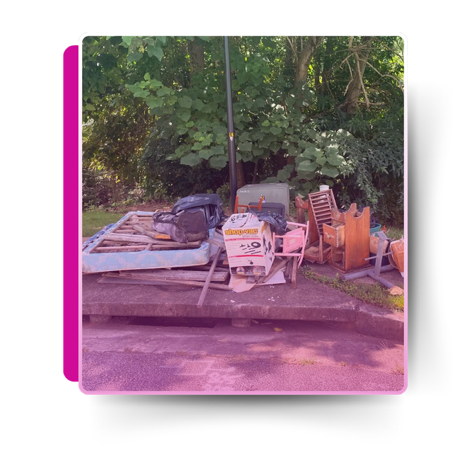 A pile of discarded house garbage in front of trees.