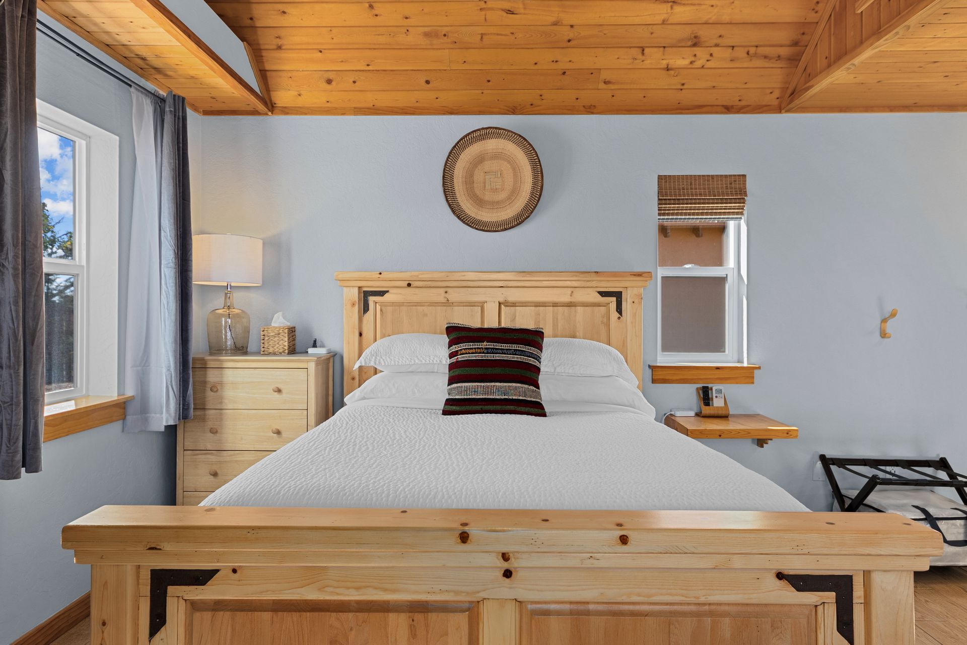 Bedroom with wooden bed, nightstand, blue walls, and rustic decor.