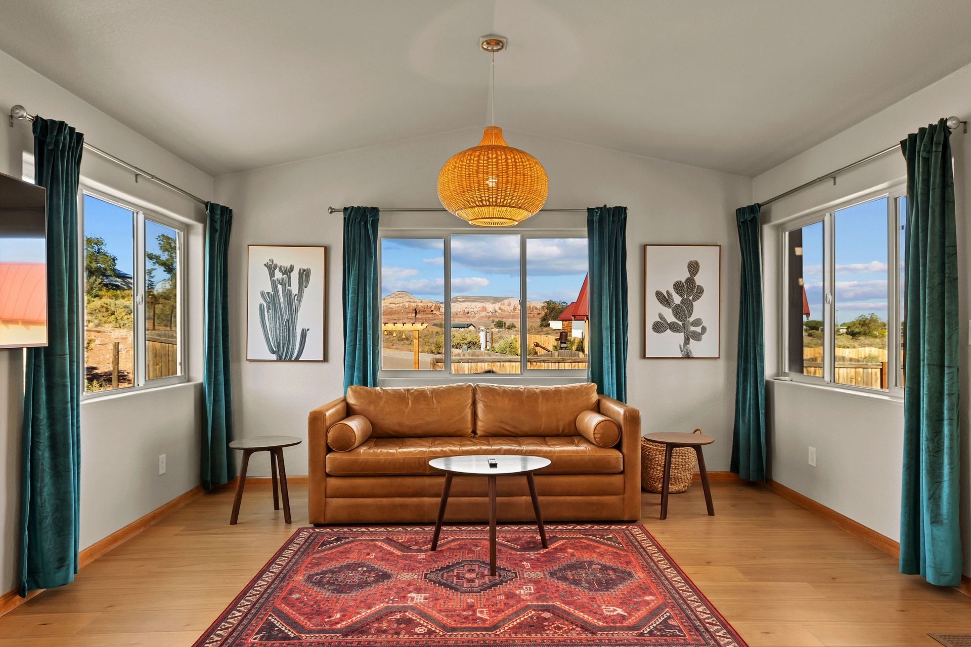 Living room with a tan leather sofa, area rug, teal curtains, and a view of the outdoors.