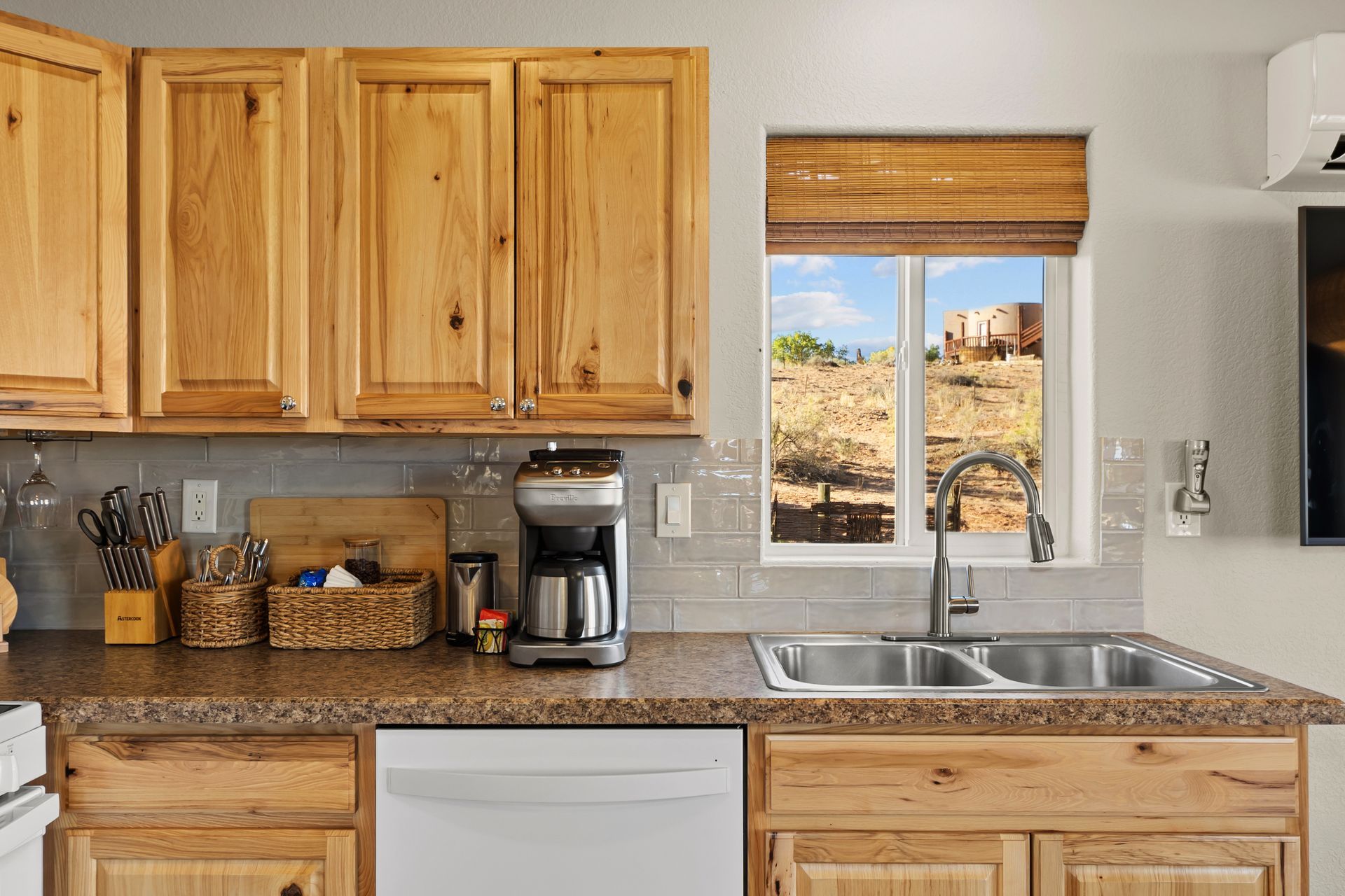 Kitchen with wooden cabinets, a sink, a coffee maker, and a window overlooking a field.