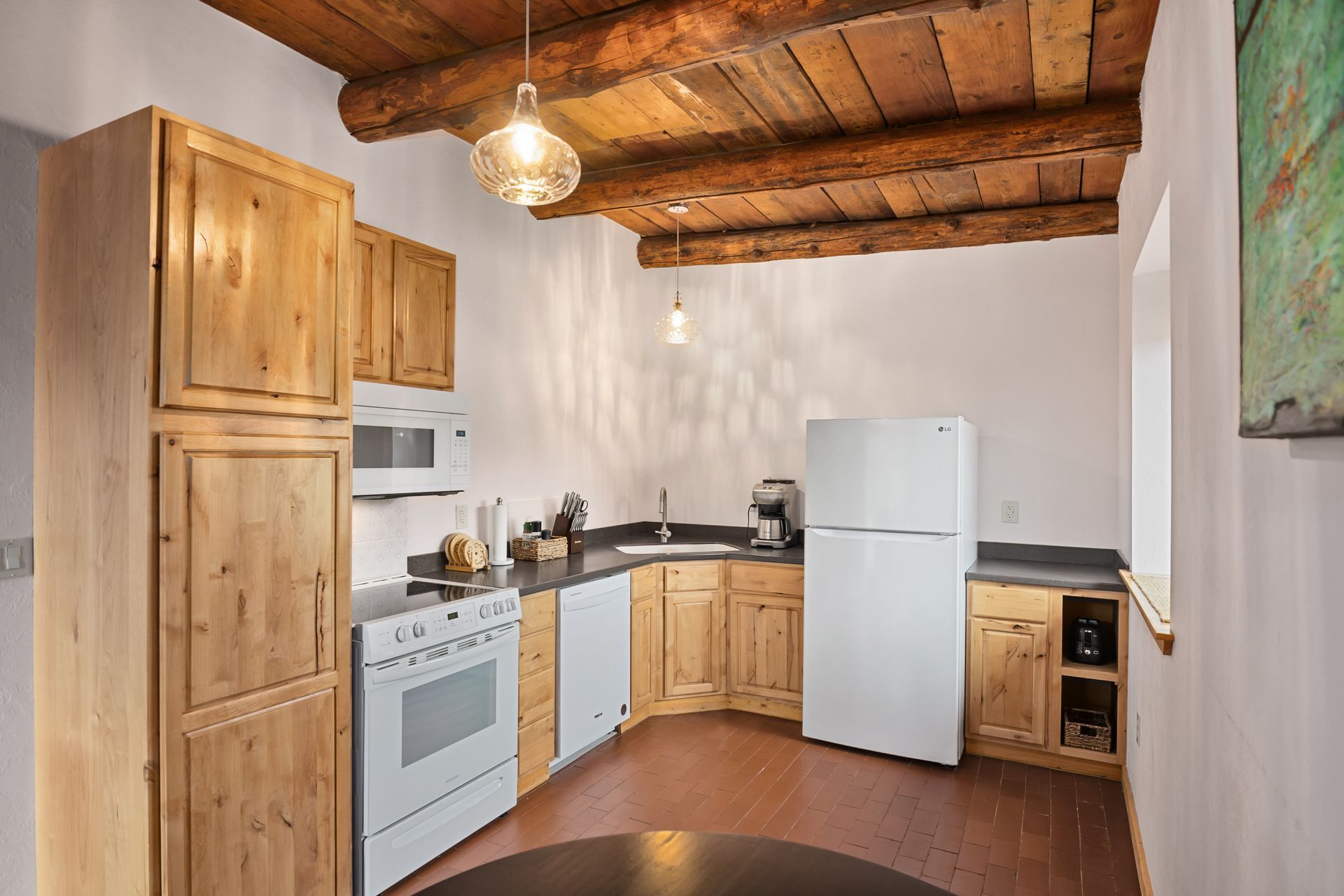 Kitchen with wooden cabinets, white appliances, and a rustic wood beam ceiling.