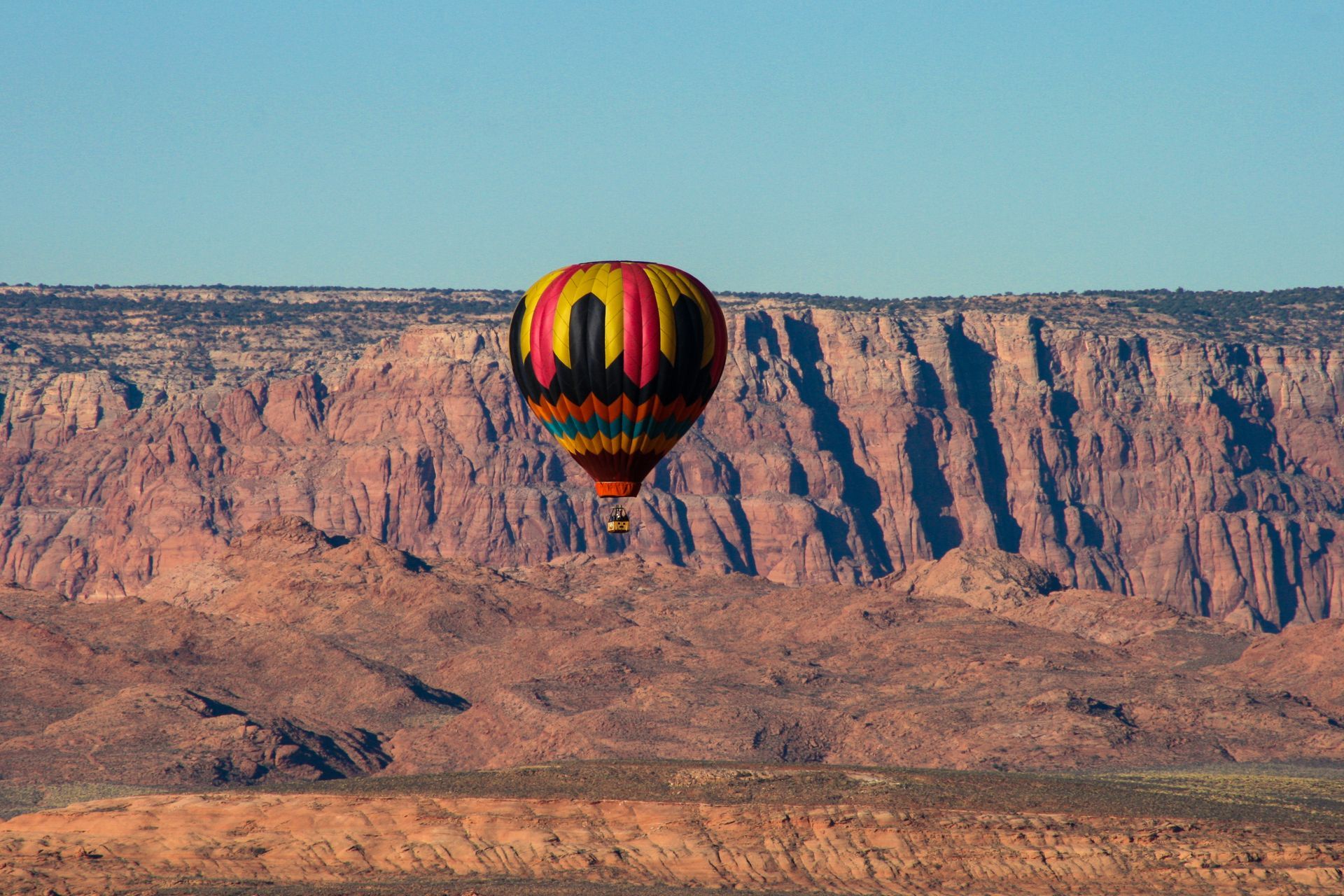 A colorful hot air balloon is flying over a desert landscape.