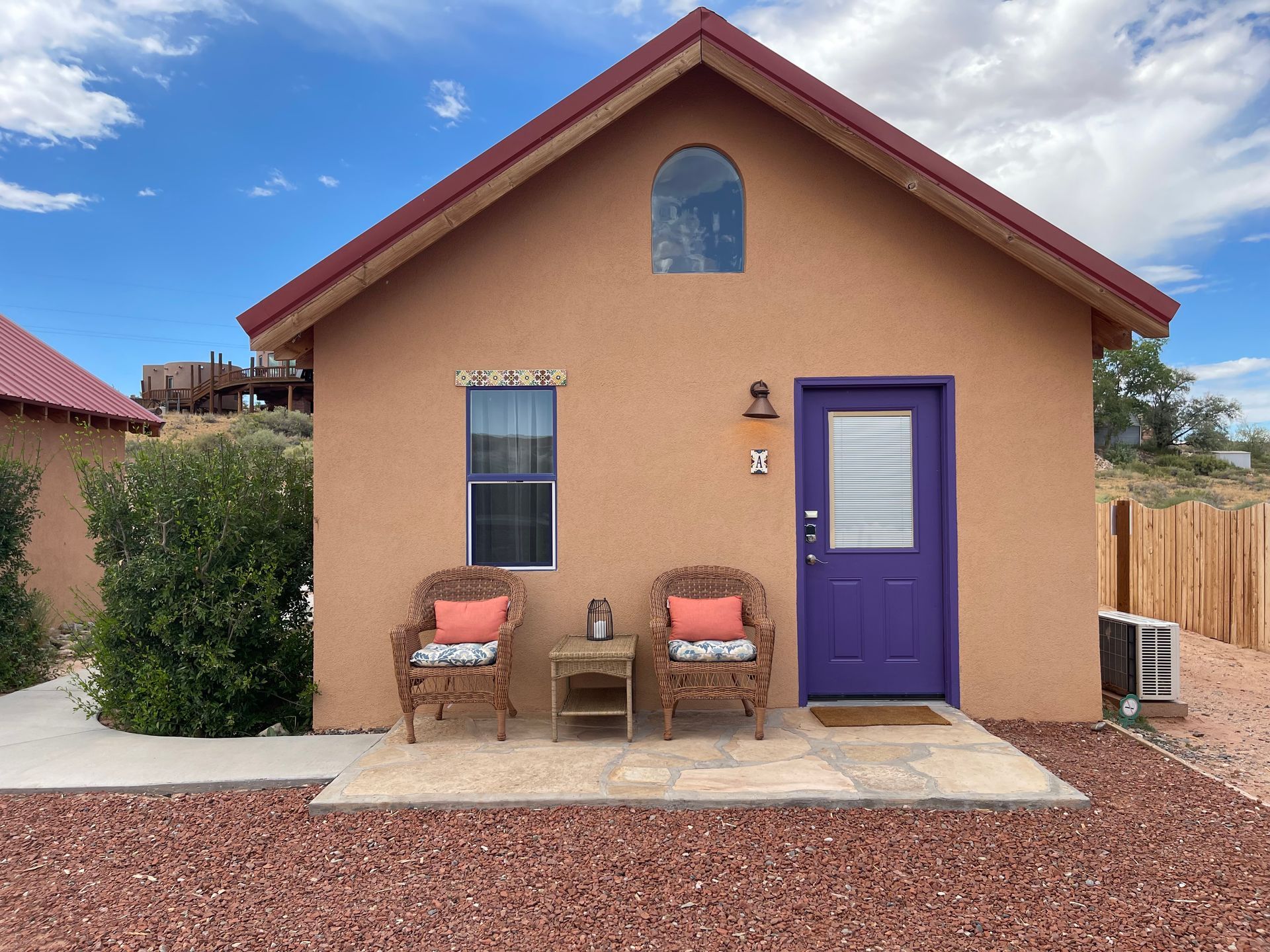 A small house with a purple door and two chairs in front of it