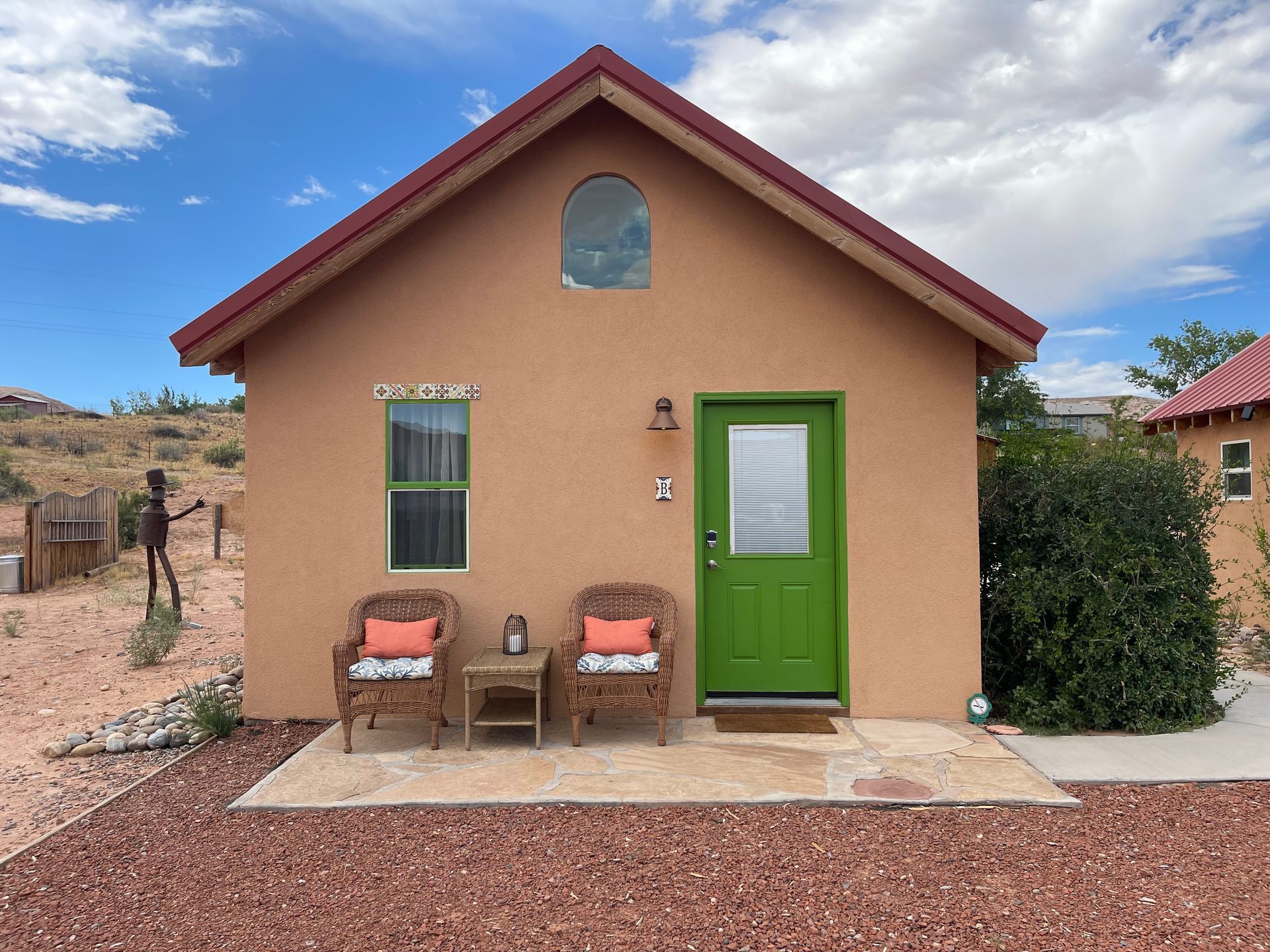 A small house with a green door and chairs in front of it