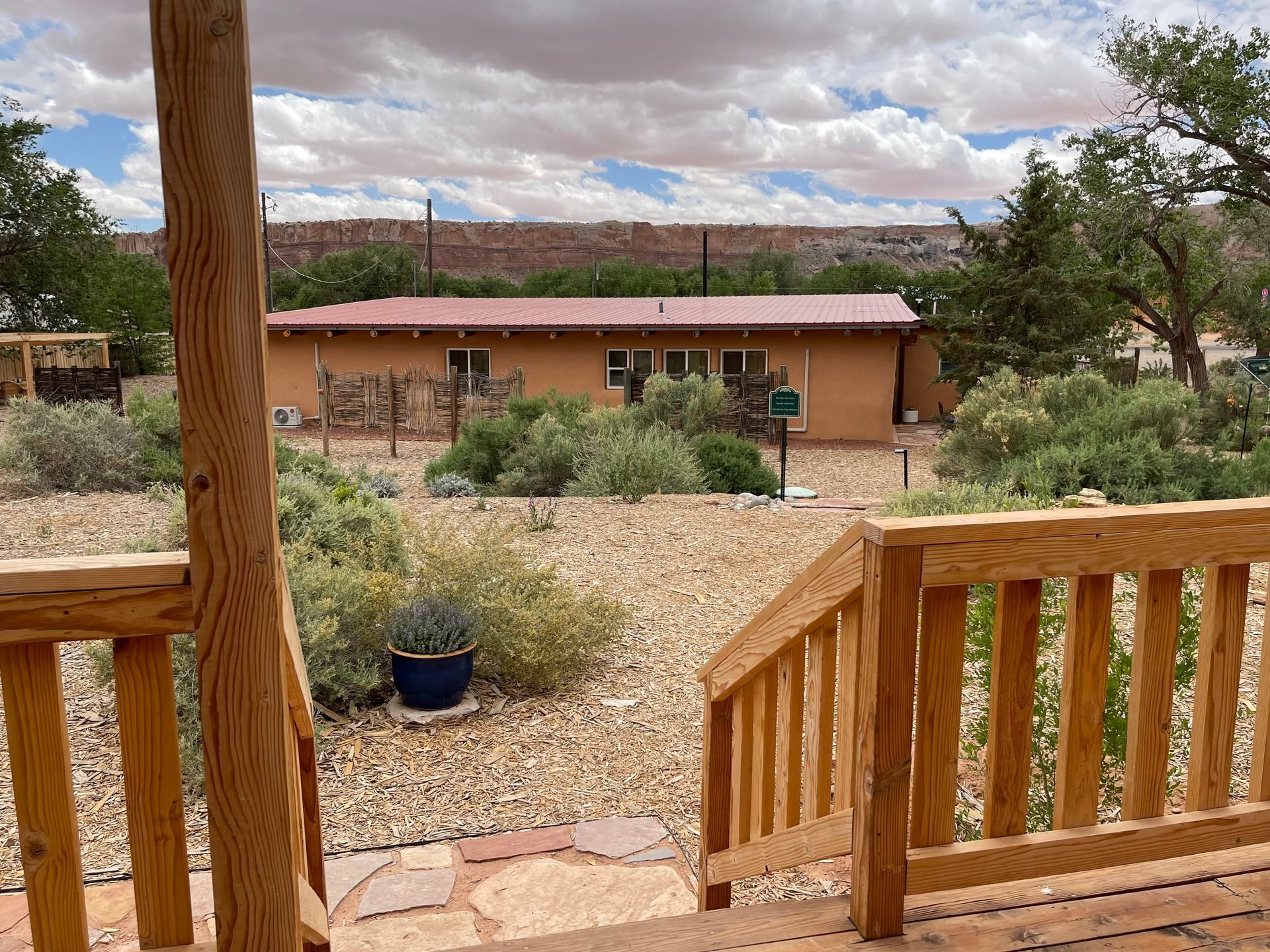 A view of a house from a wooden deck with stairs leading up to it.