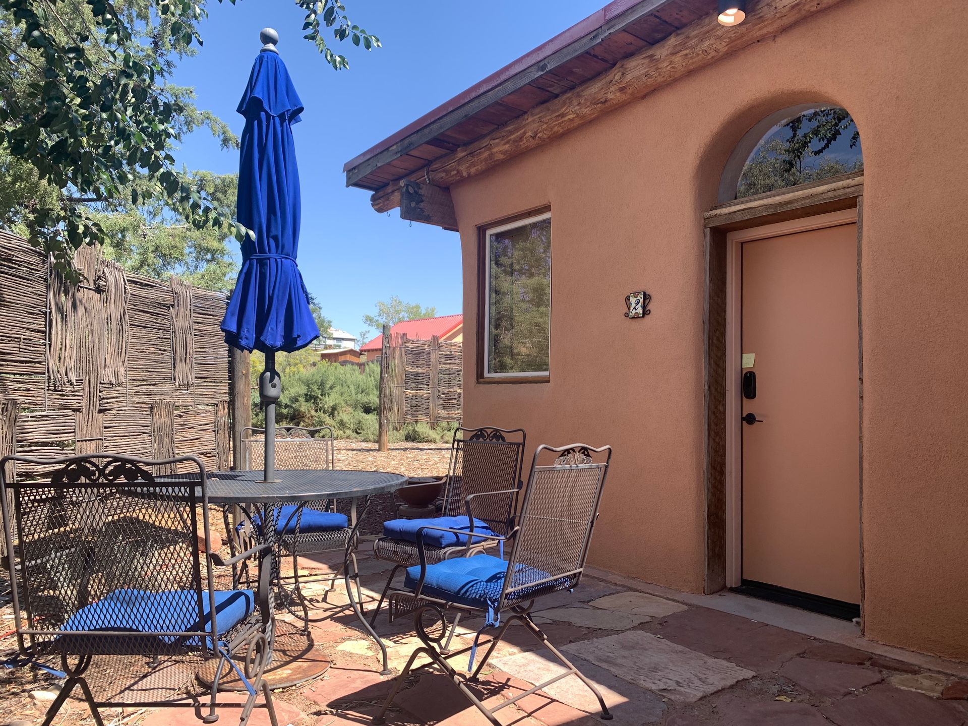 A patio with a table and chairs and a blue umbrella