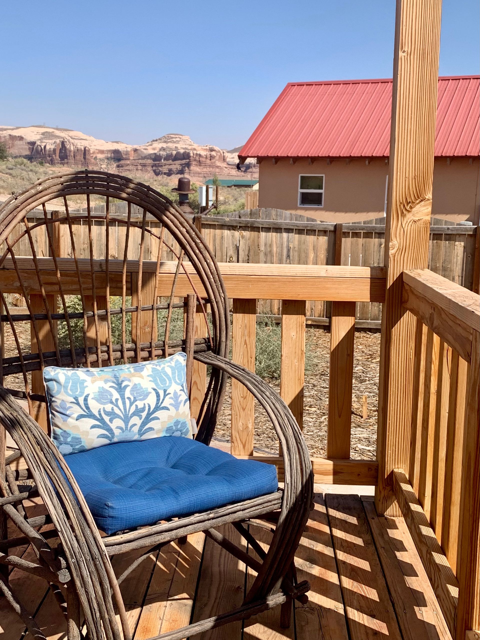 A wicker chair with a blue cushion sits on a deck