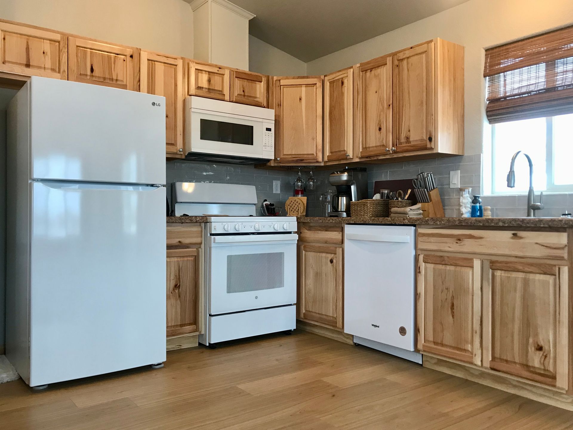 A kitchen with wooden cabinets , a white refrigerator , a stove , a microwave and a sink.