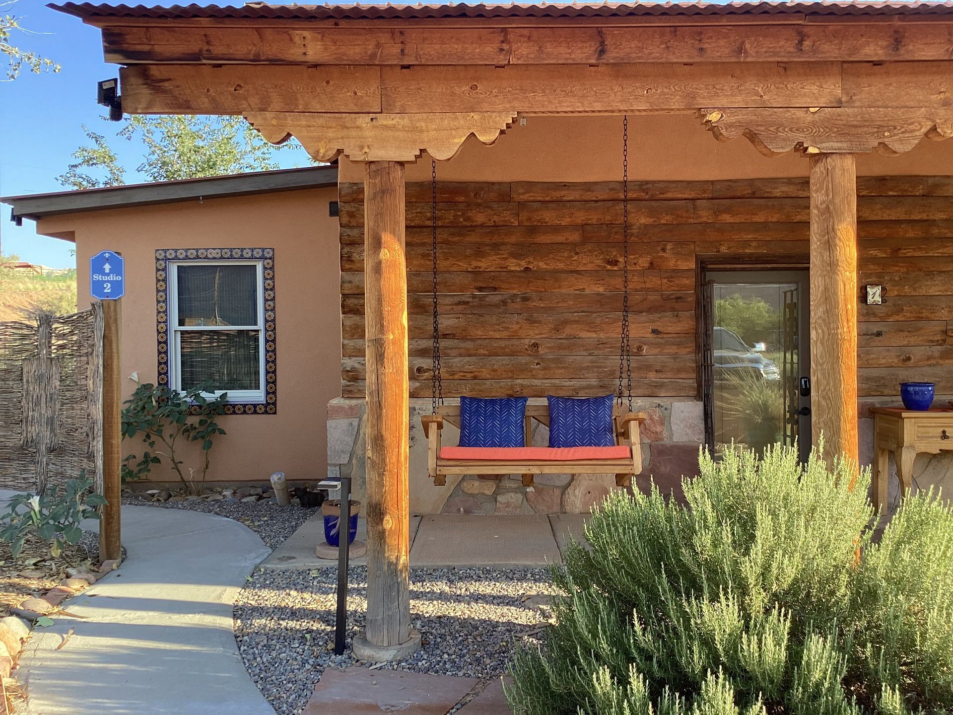 Rustic cabin with porch swing, blue cushions, and front door, in outdoor setting.