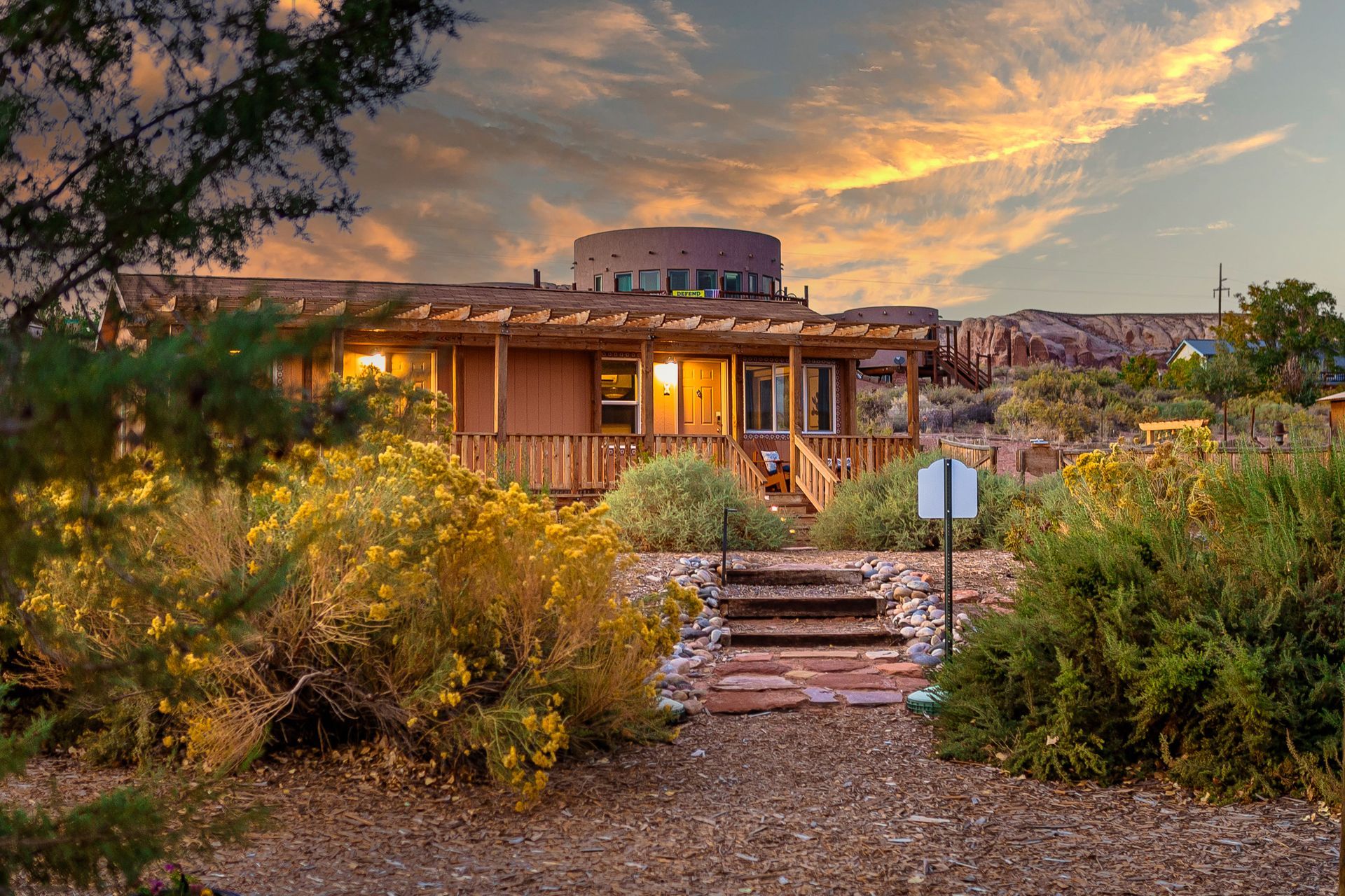 A house in the middle of a desert surrounded by trees and bushes.