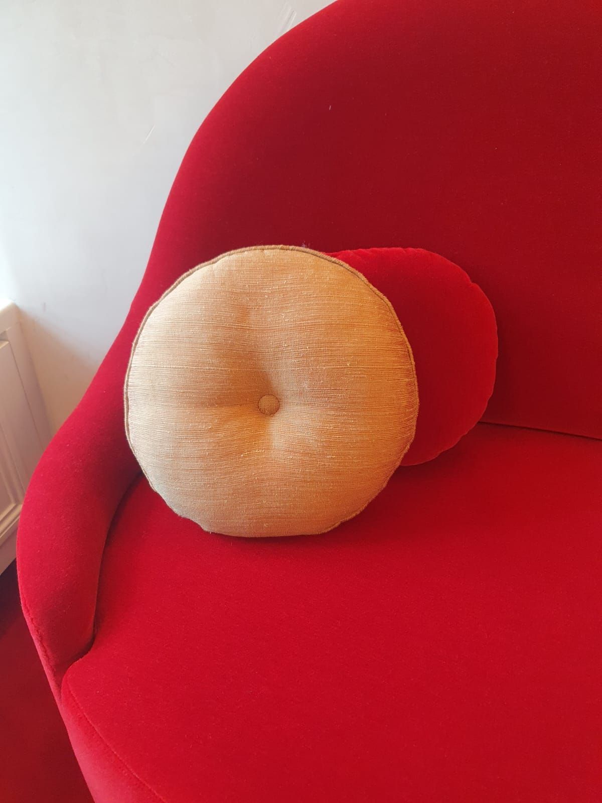 Un fauteuil rouge avec deux coussins ronds ; un beige et un rouge.