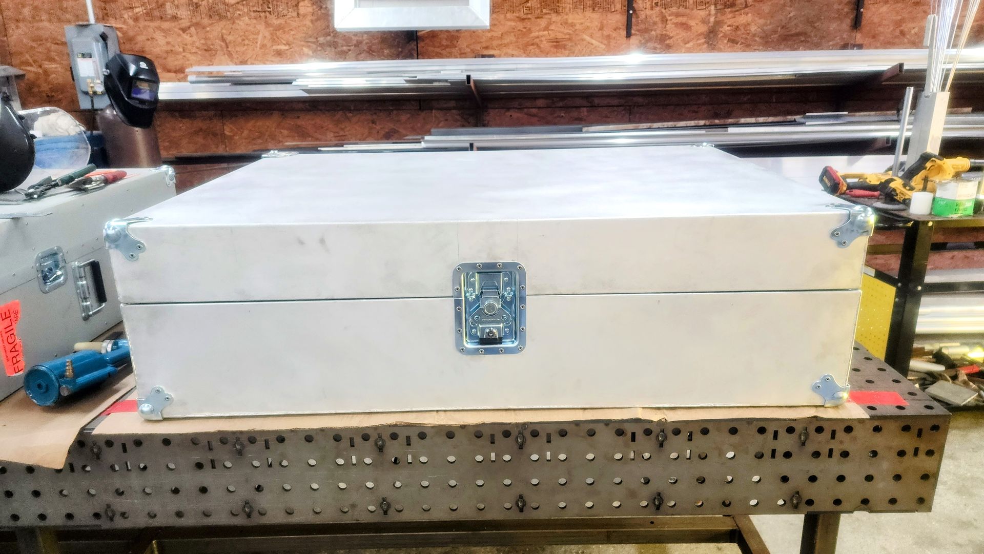White wooden box with metal hardware, sitting on a metal table in a workshop.