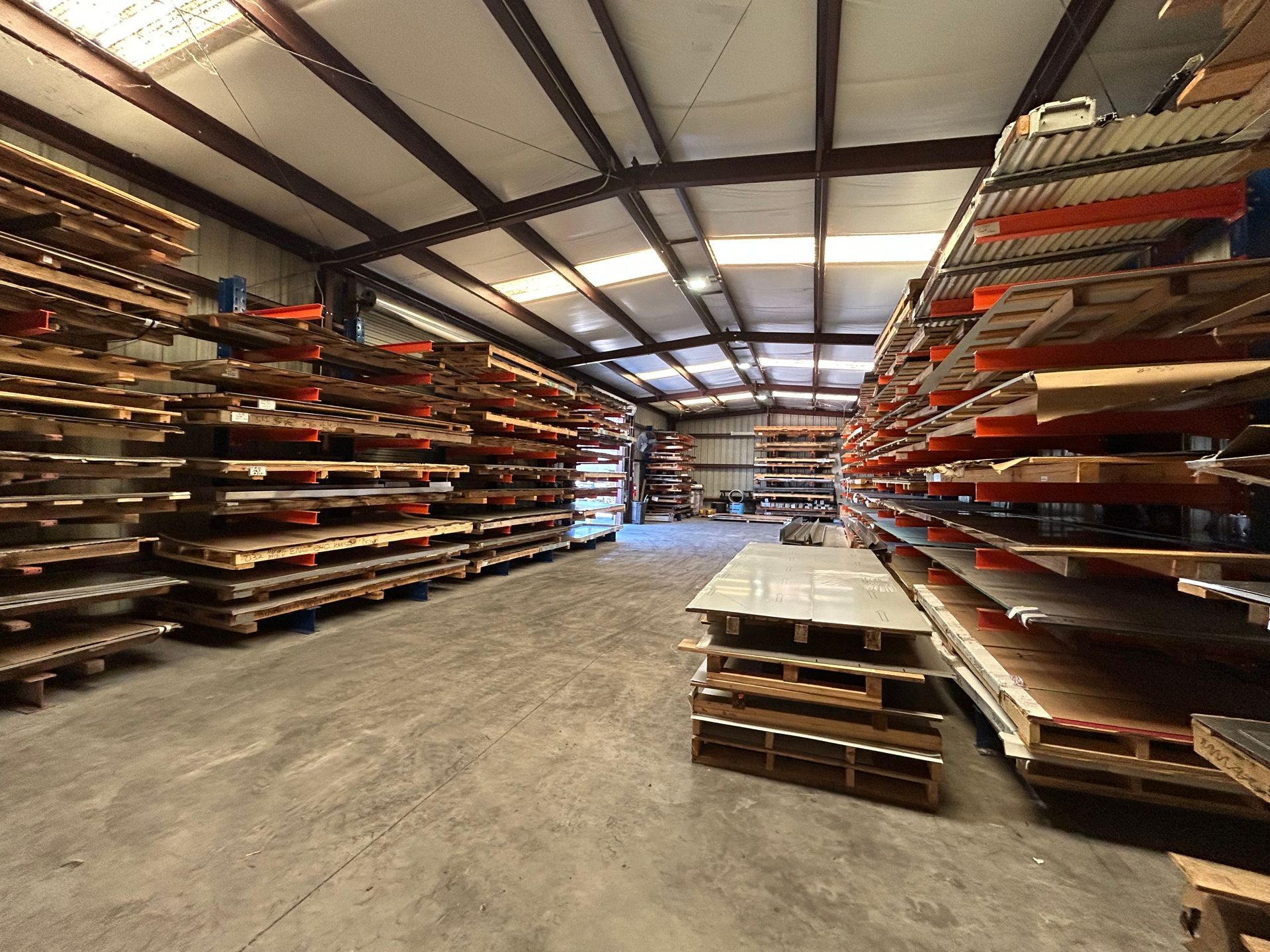 Warehouse interior with metal sheets stacked on shelves.