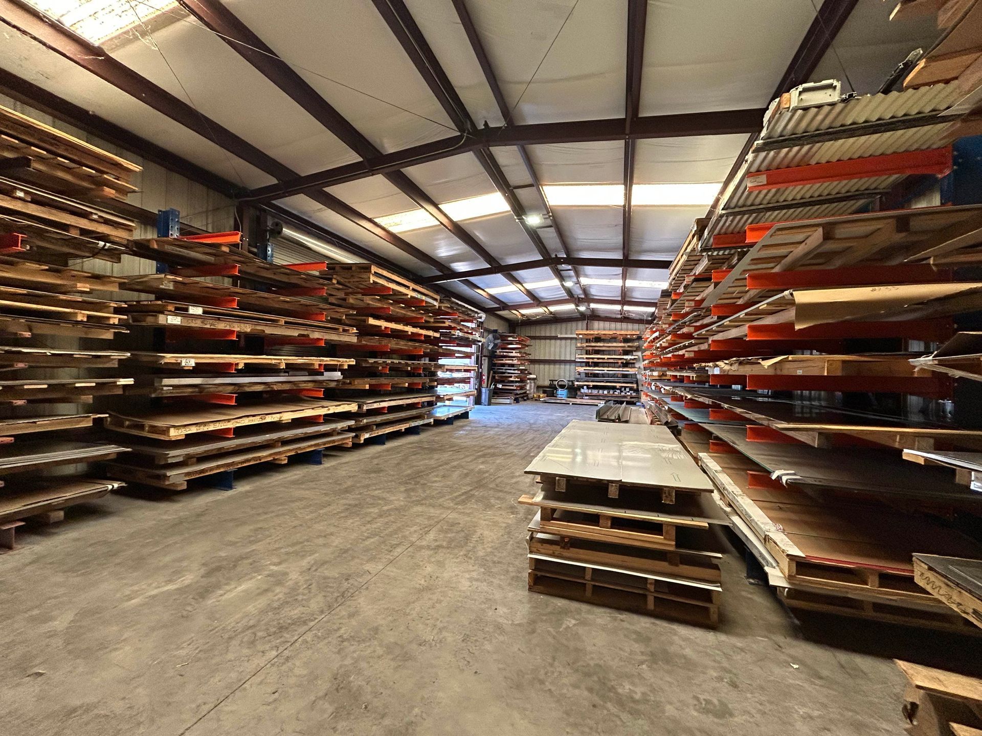 Warehouse interior with shelves stacked high with wood and metal sheets.