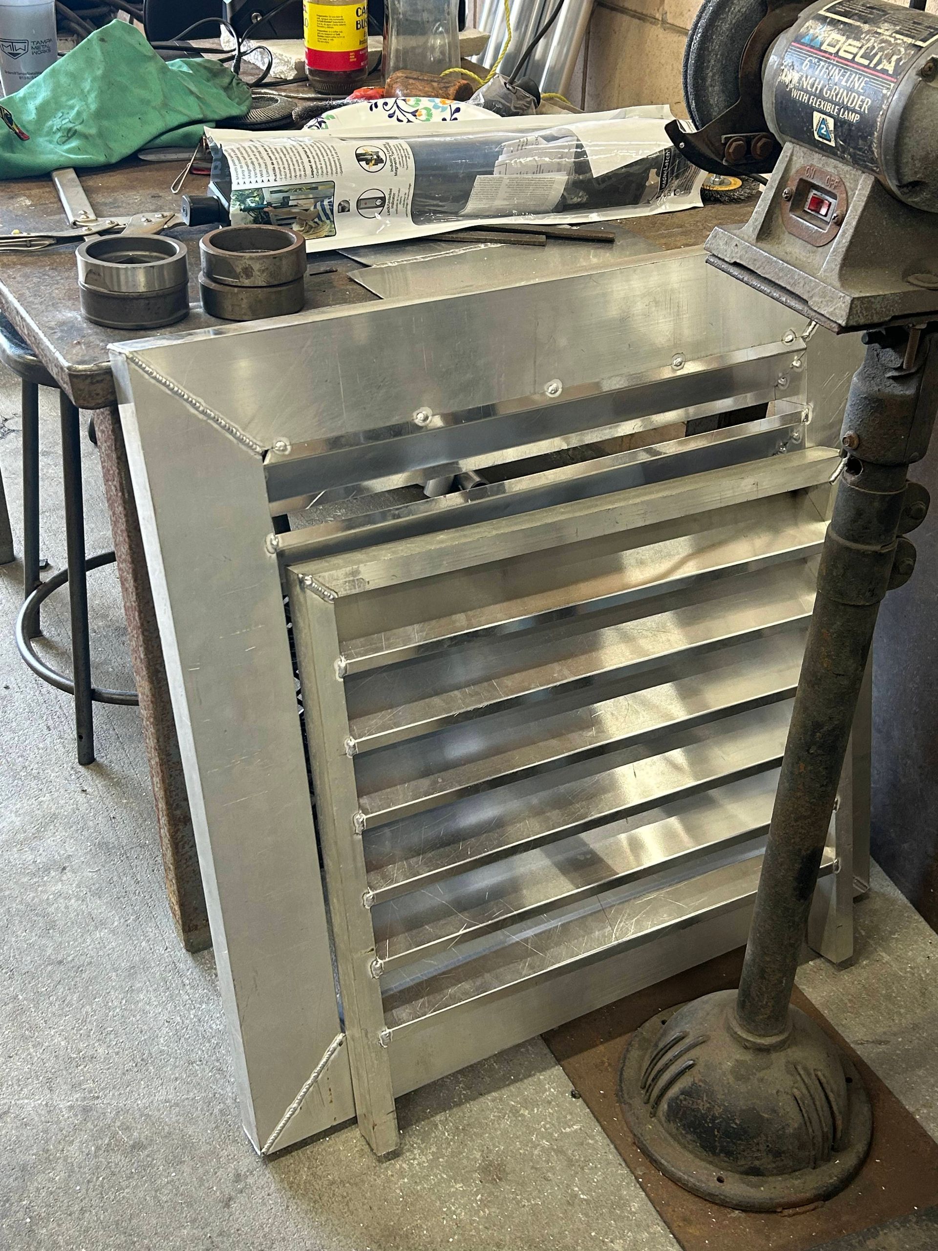 Aluminum vent with angled slats in a workshop setting.