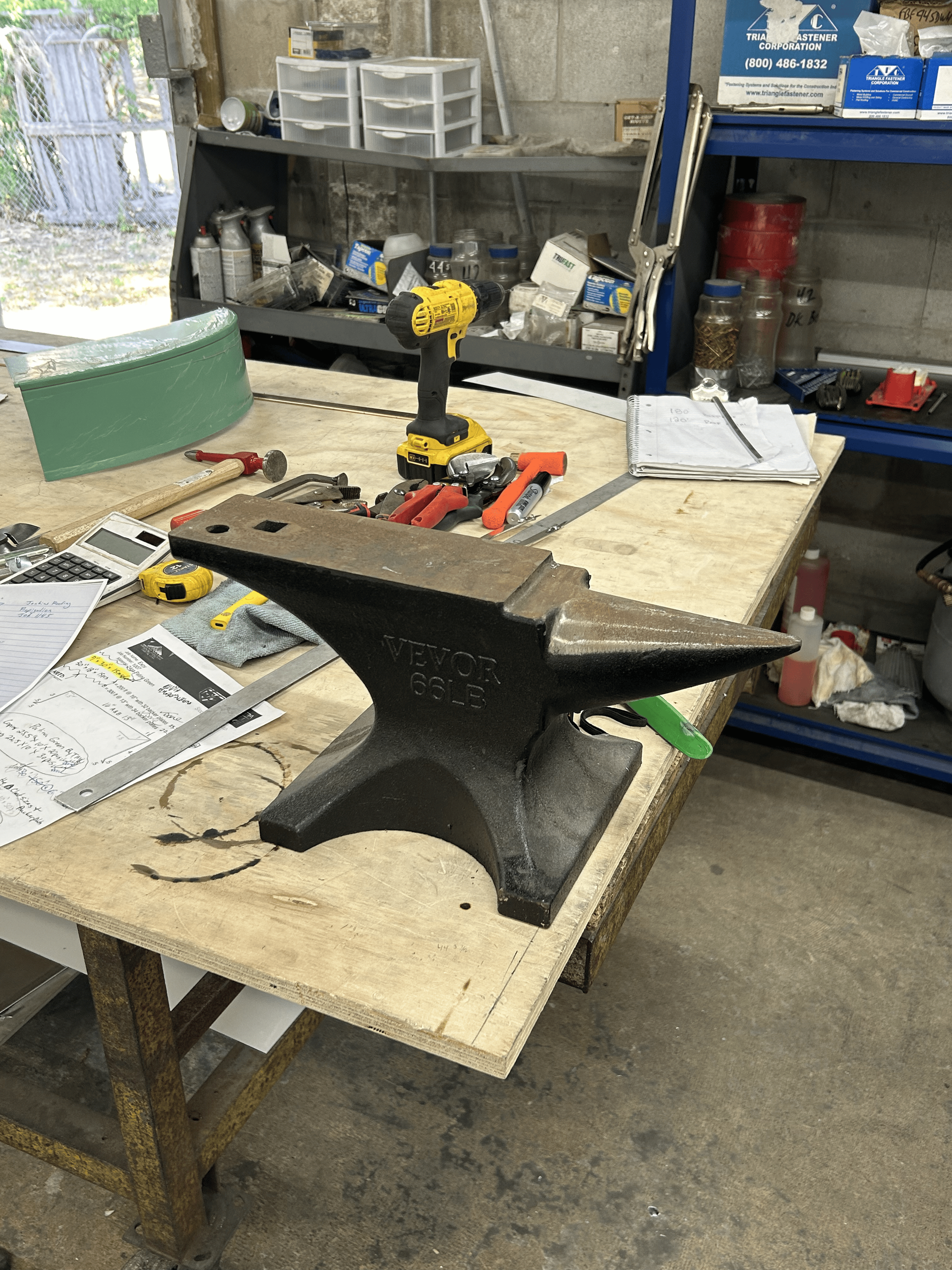 Anvil on workbench with tools in a workshop.