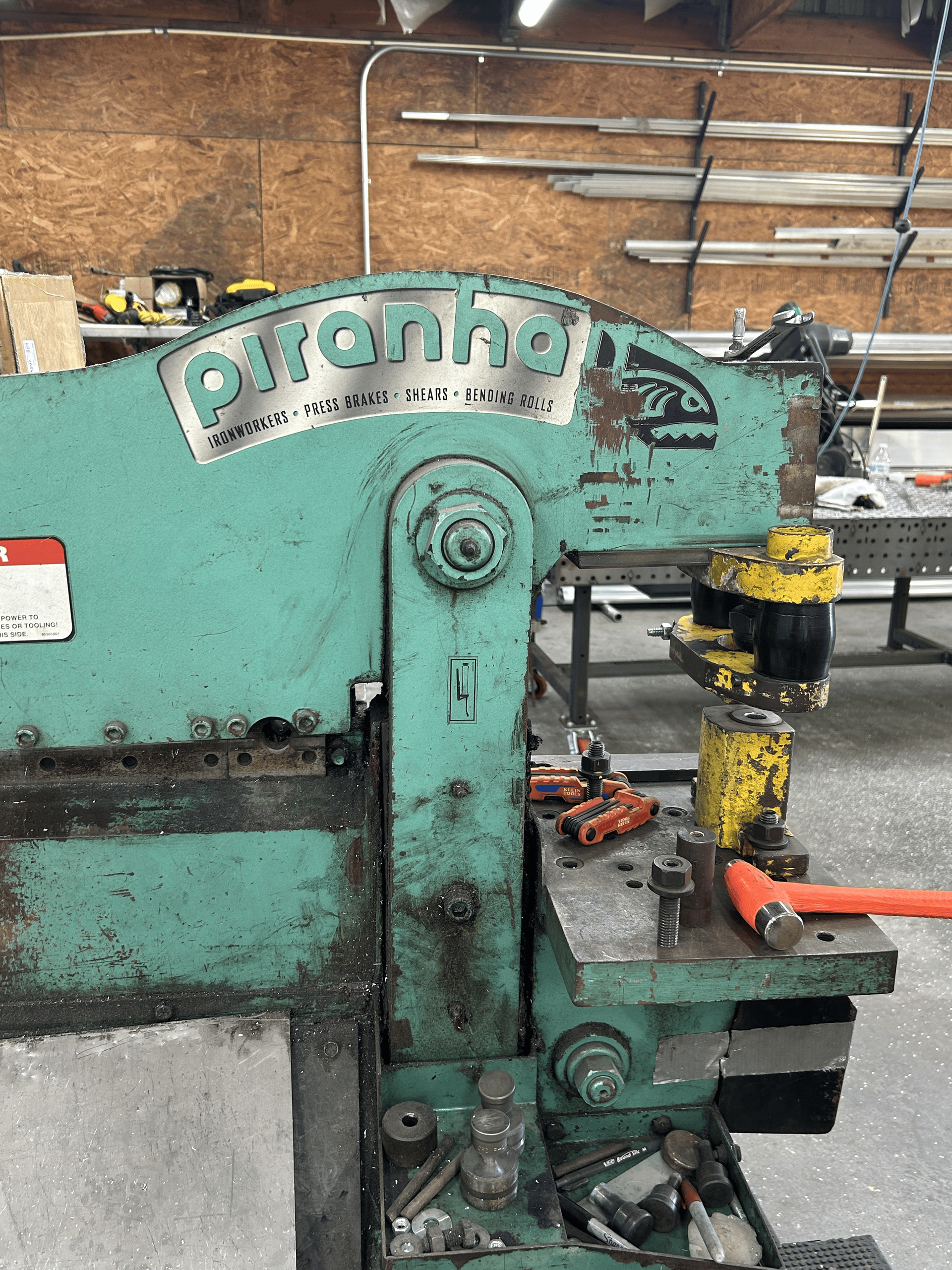 Green Piranha metalworking machine in a workshop, with tools scattered nearby.