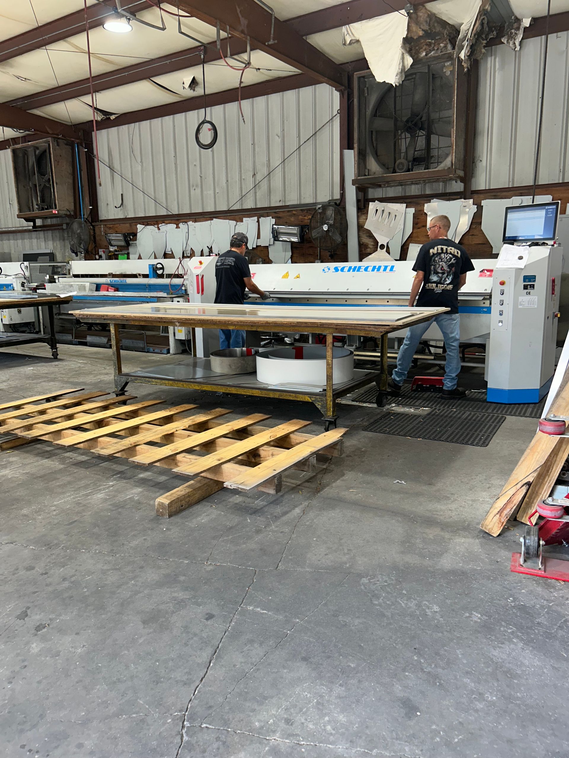 Two men working in a factory setting, operating a large industrial machine with a control panel.
