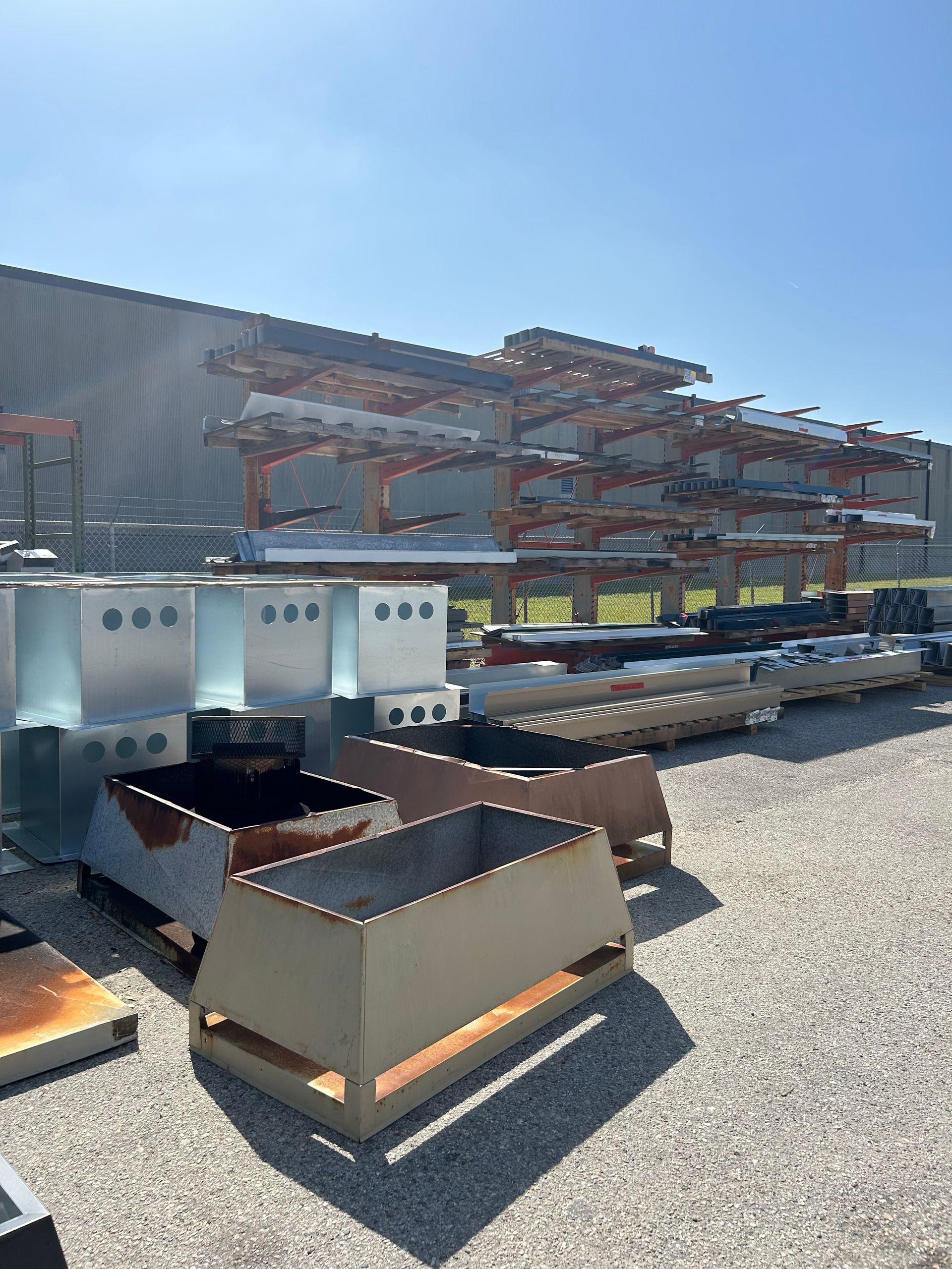 Metal components and storage racks outside on a sunny day.