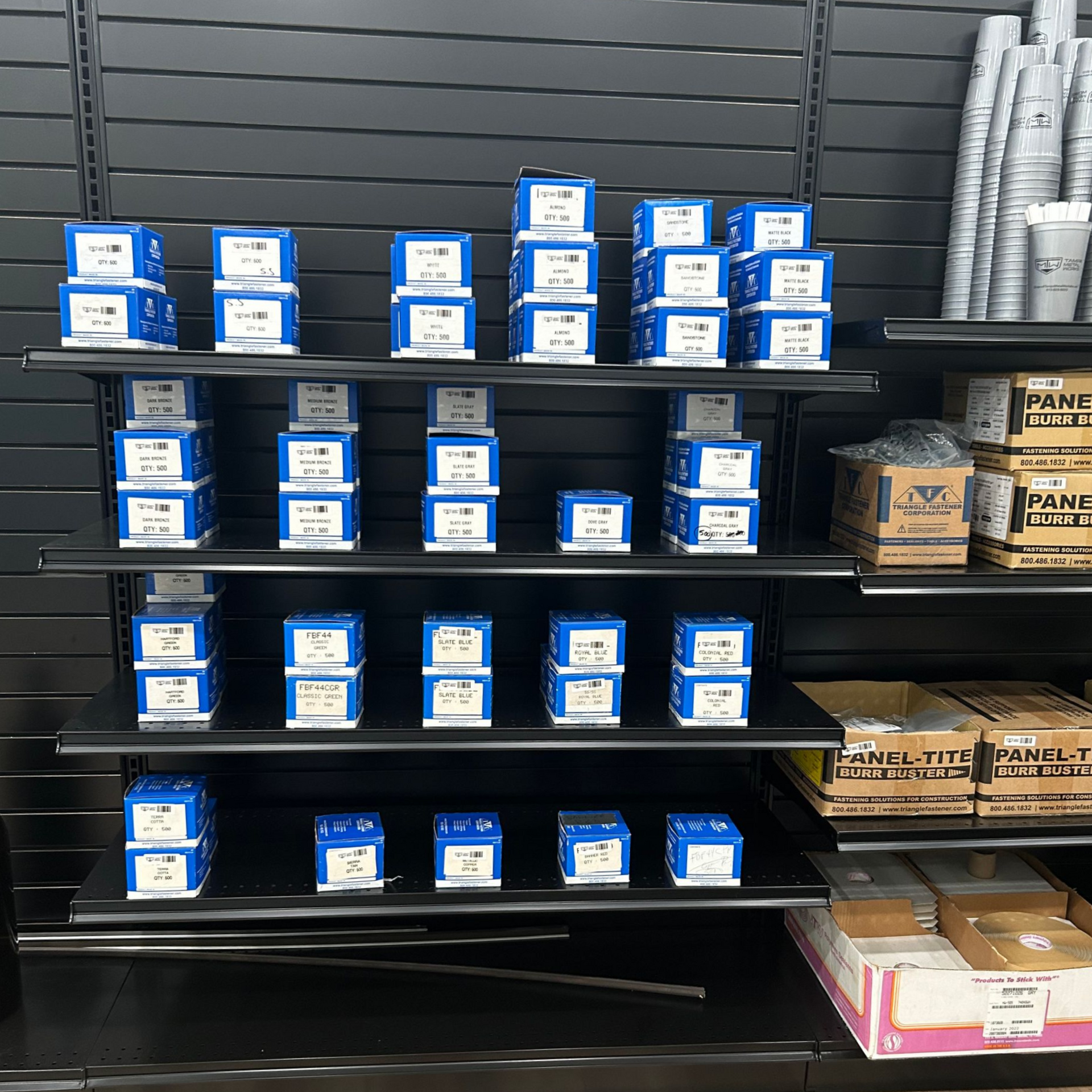 Shelves stocked with blue and white boxes, likely containing industrial parts, in a hardware store.