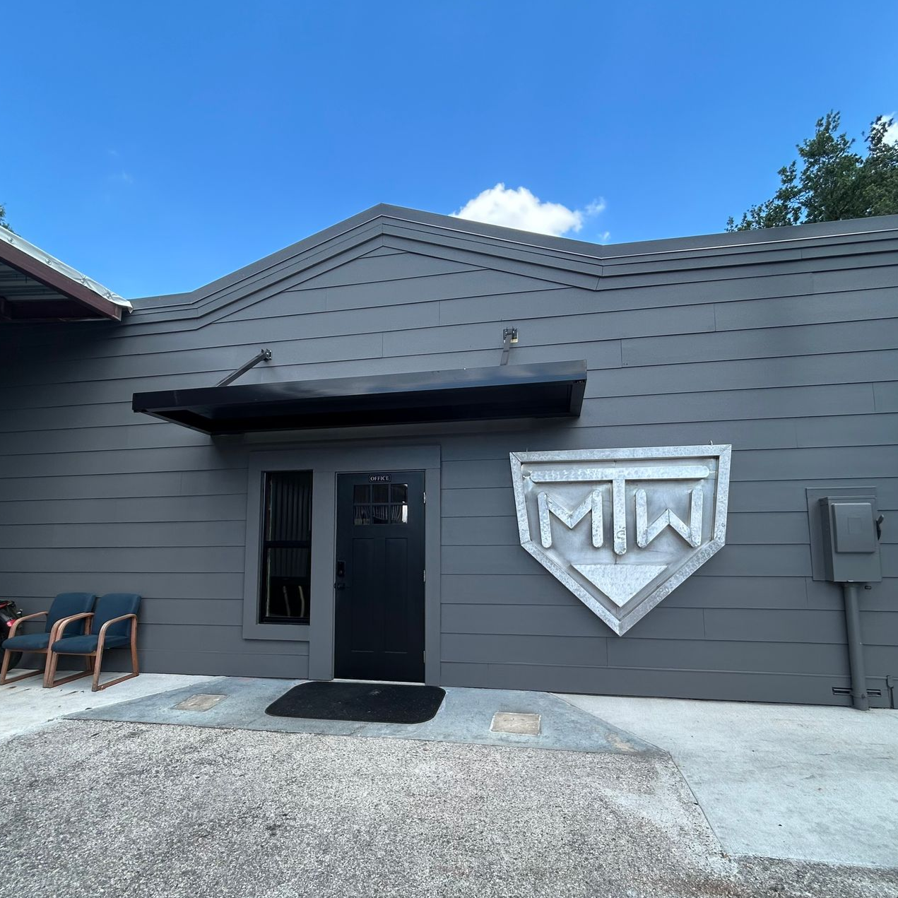 Gray building with black door, awning, and large metal 