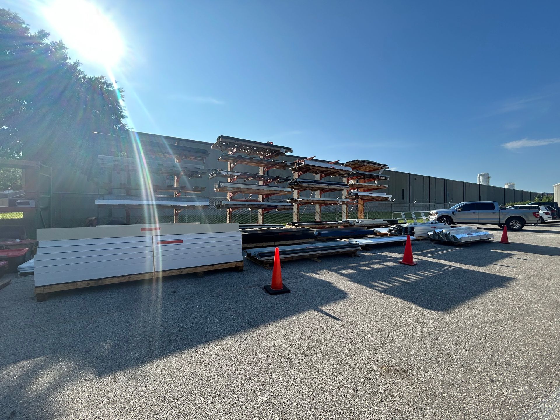 Sunlit outdoor construction site with materials on racks and pallets.