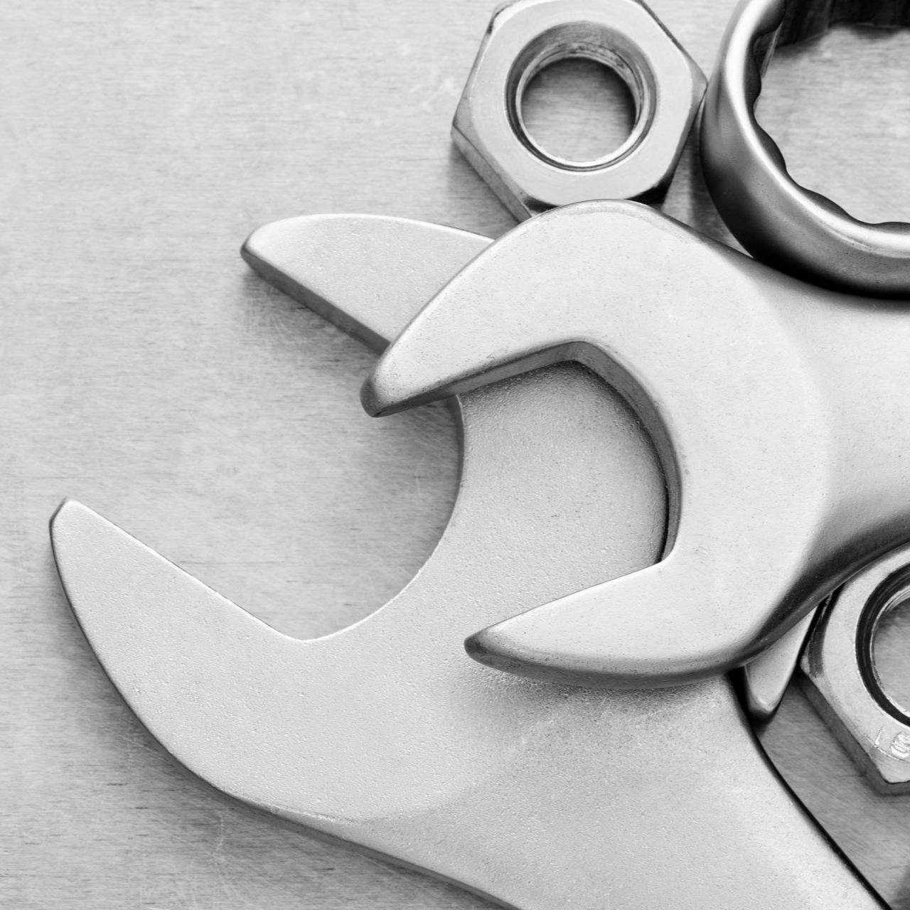 Wrench and nuts on a light-colored surface.