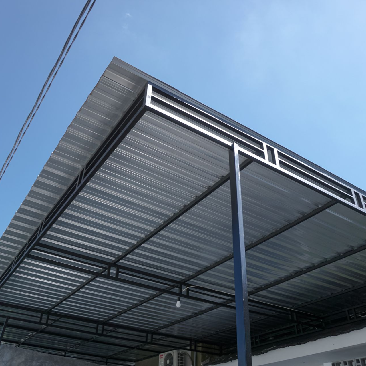 Metal carport with corrugated roof against a blue sky.