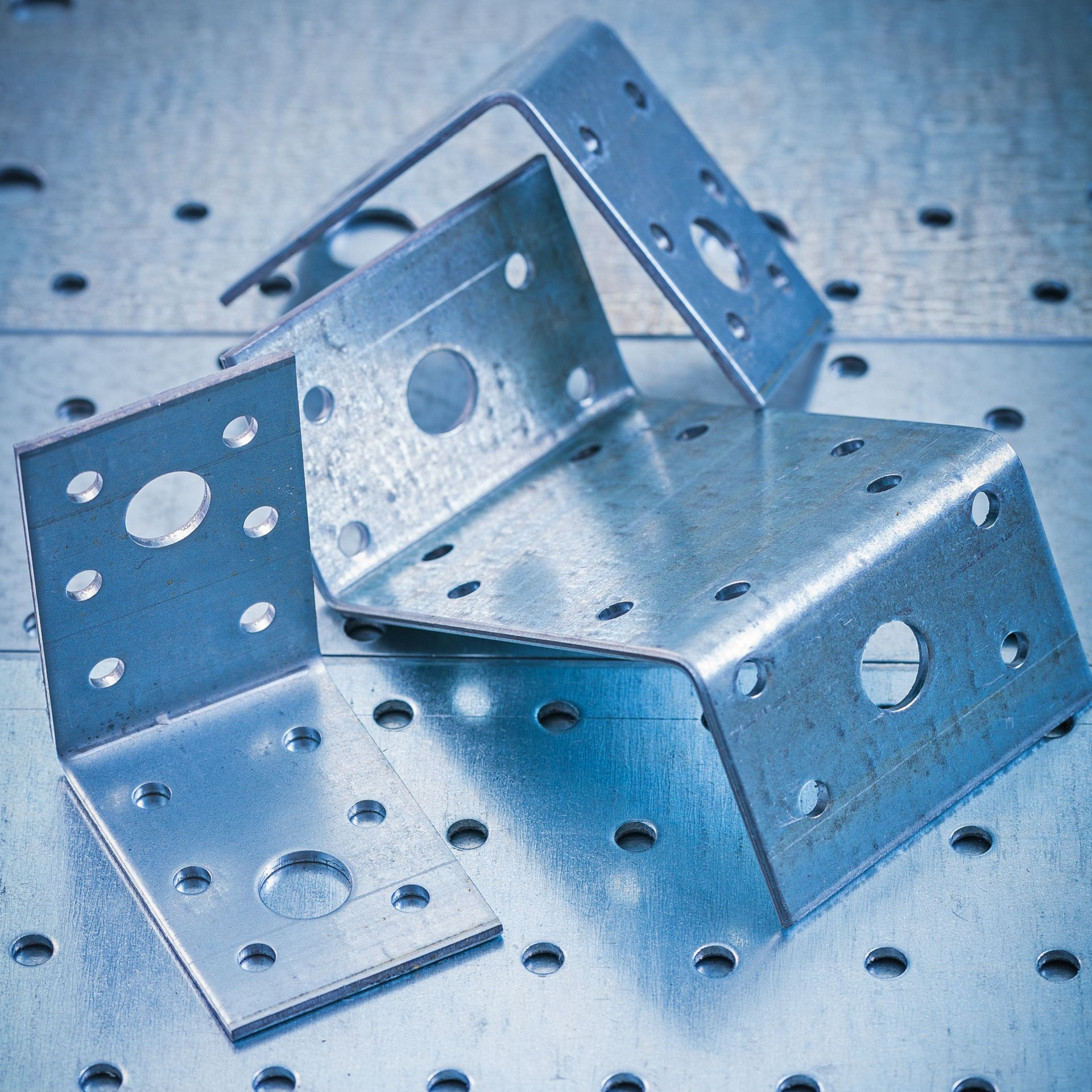 Metal L-brackets with various sized holes for securing wood pieces on a silver background.