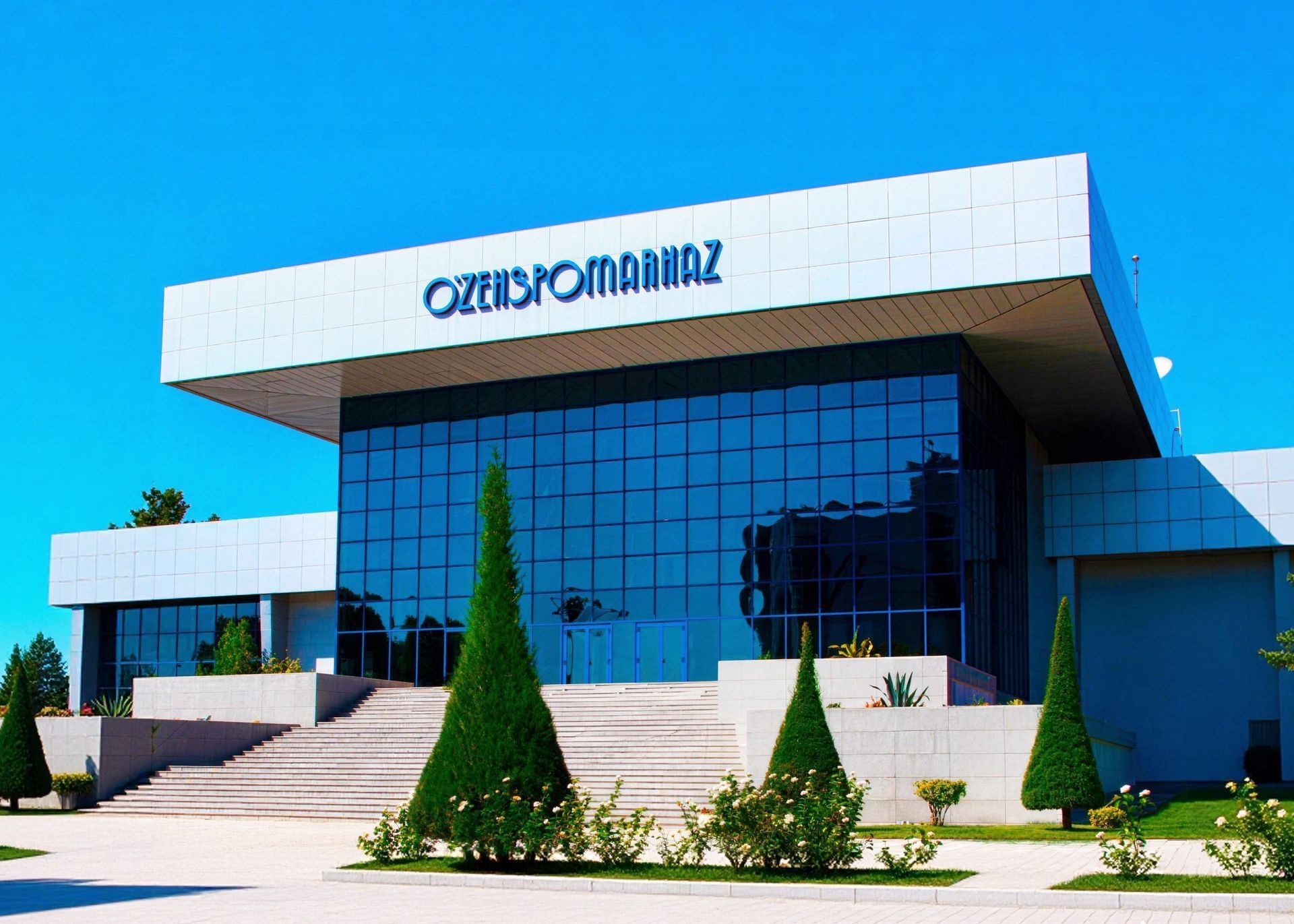 Interior of a modern building lobby with people, geometric wood and metal walls, pillars, and red curtains.