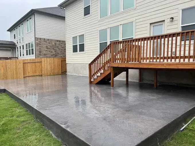 A large concrete deck with stairs leading up to it in front of a house.