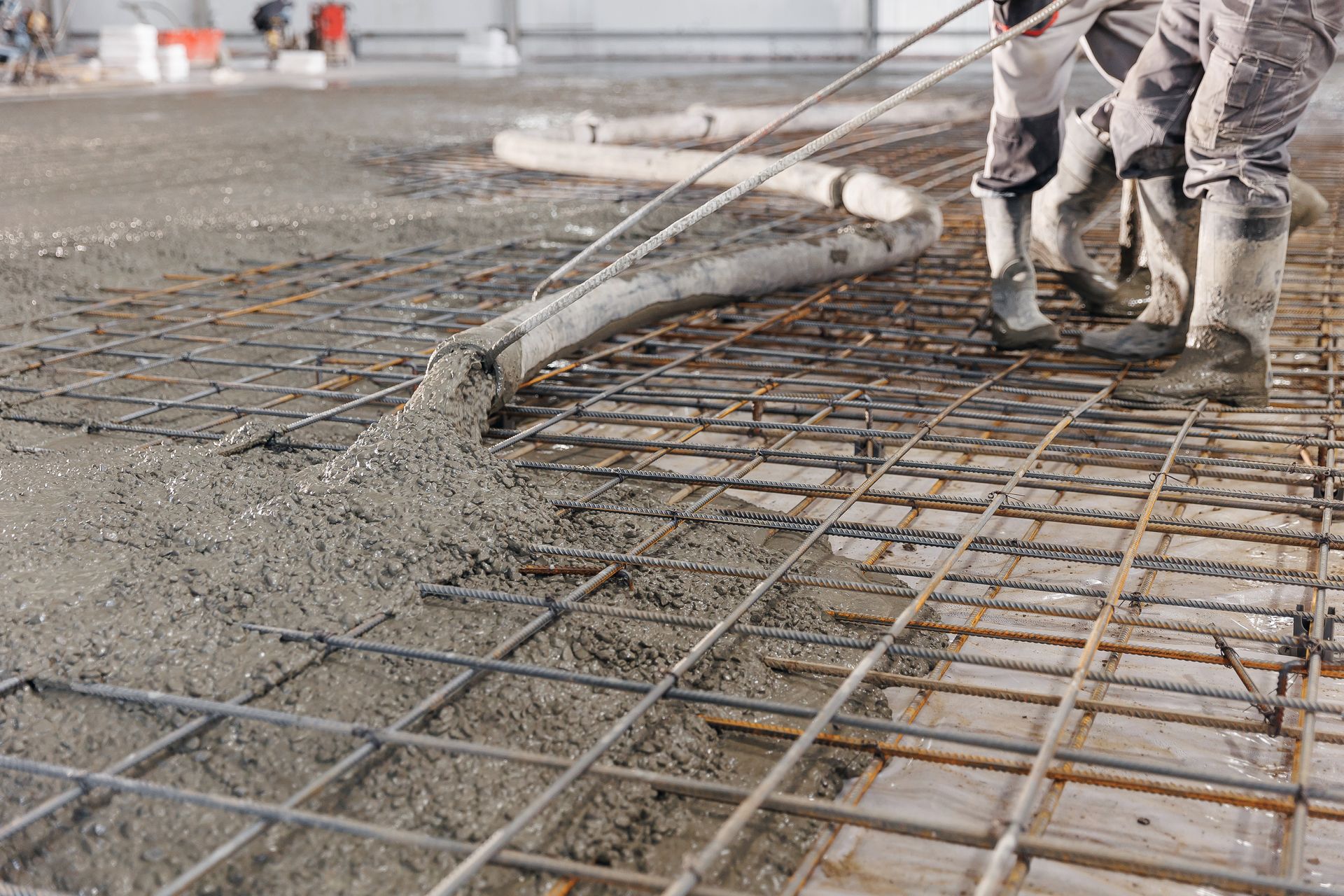 A group of construction workers are pouring concrete on a concrete floor.