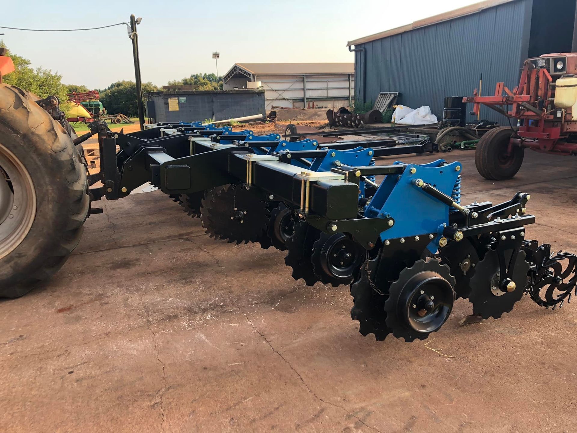 A Tractor Pulling a Large Blue and Black Farming Implement — Australian Mobile Welding Pty Ltd in Atherton, QLD