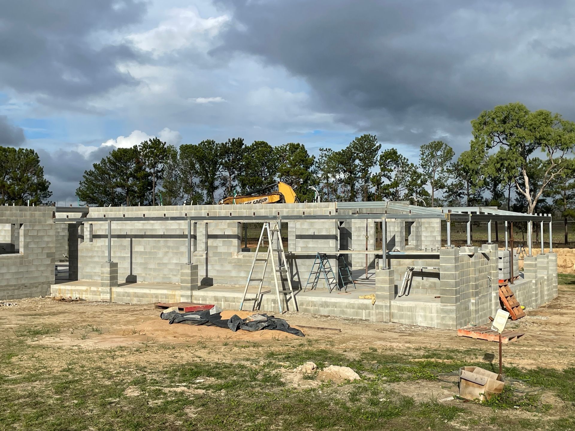 White garage with three doors, gravel driveway, and a carport under a sunny sky — Australian Mobile Welding Pty Ltd in Cooktown, QLD