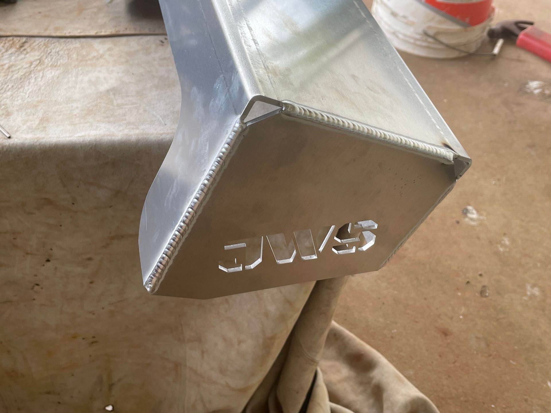 Aluminum metal fabrication with welded seams and the letters 