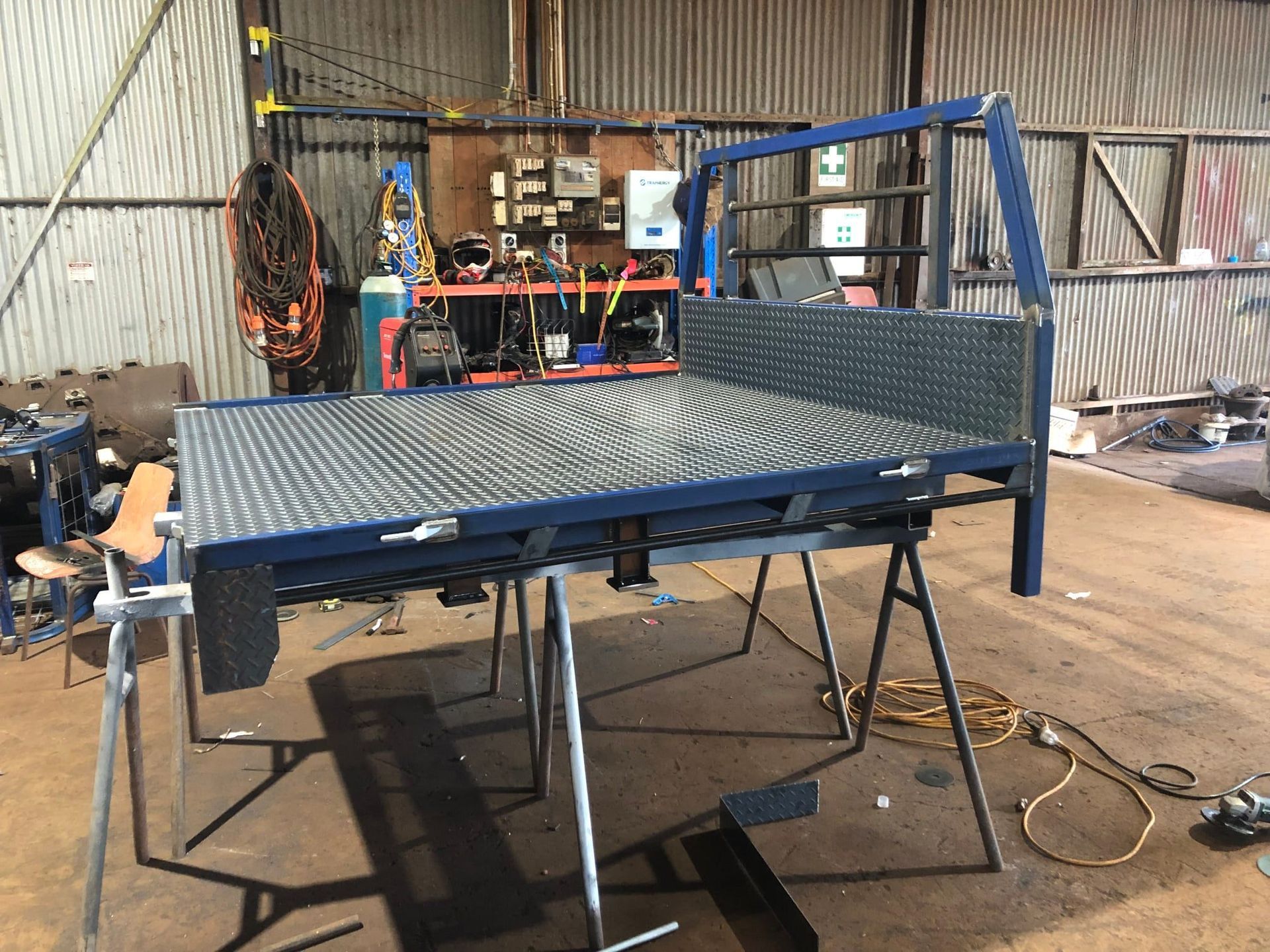 Blue Metal Truck Bed Frame on Sawhorses in a Workshop — Australian Mobile Welding Pty Ltd in Atherton, QLD