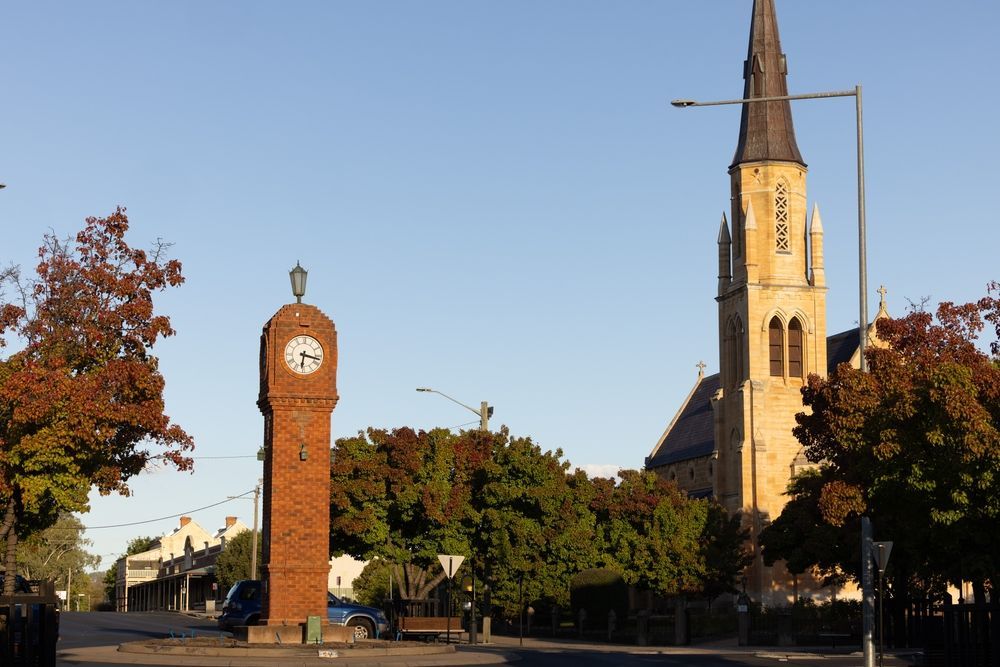 A Clock Tower Stands in the Foreground Sandstone-colored Church — Australian Mobile Welding Pty Ltd in Mudgee, NSW