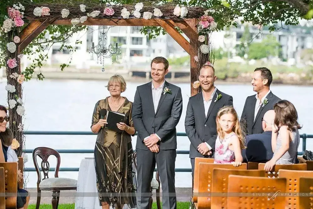 A Group Of People Standing Under A Wooden Arch At A Wedding Ceremony — Carolynn Farmer-Celebrant In Emu Park, QLD