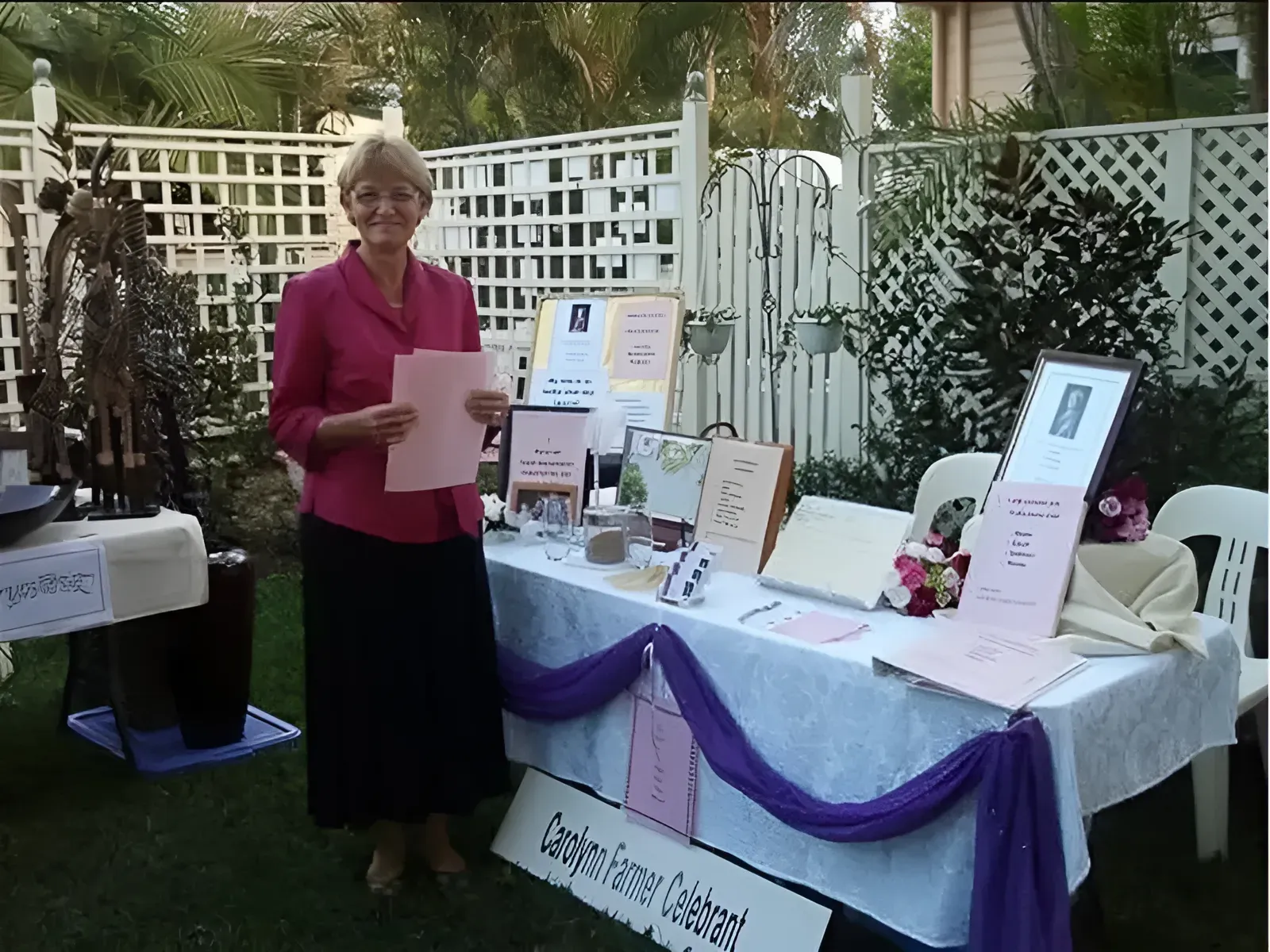 A Woman Stands In Front Of A Table That Has A Sign — Carolynn Farmer-Celebrant In Emu Park, QLD