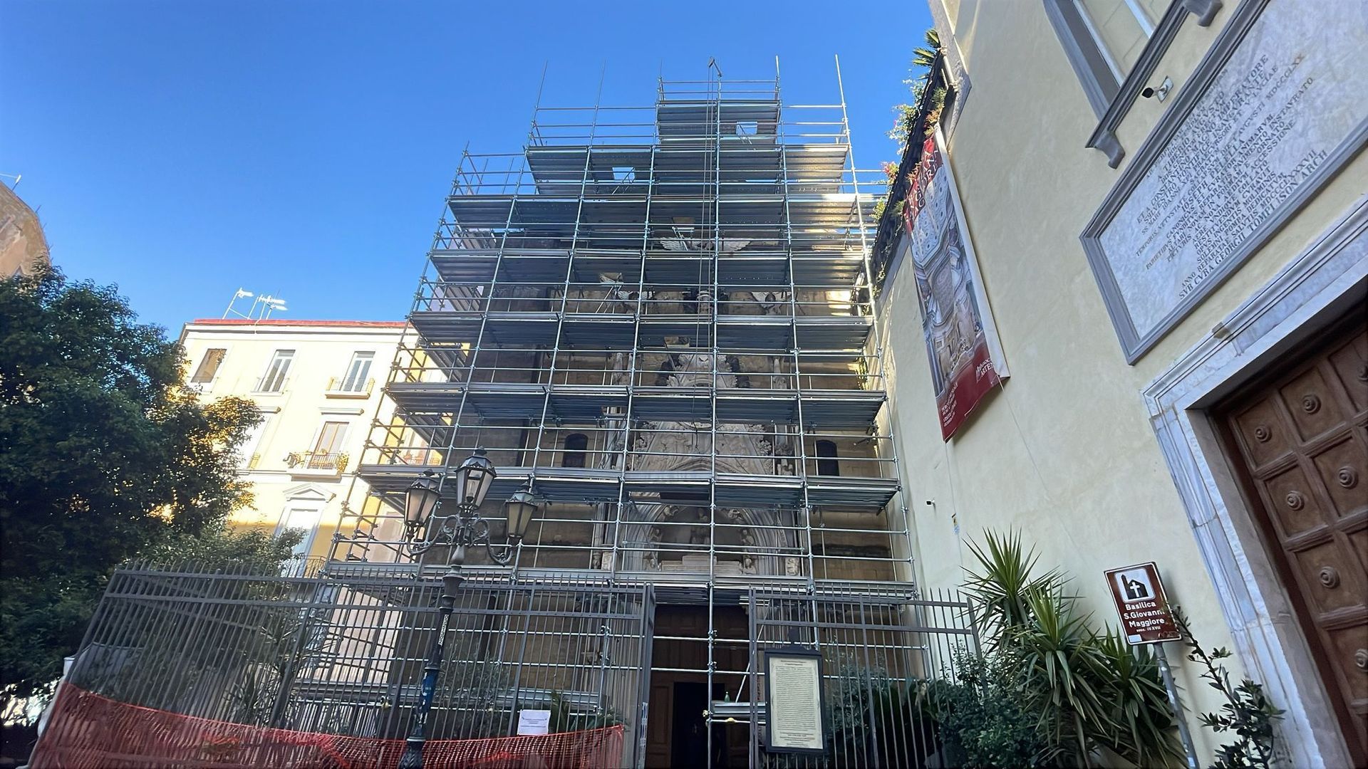 Edificio in fase di ristrutturazione, coperto da impalcature, contro un cielo azzurro brillante.
