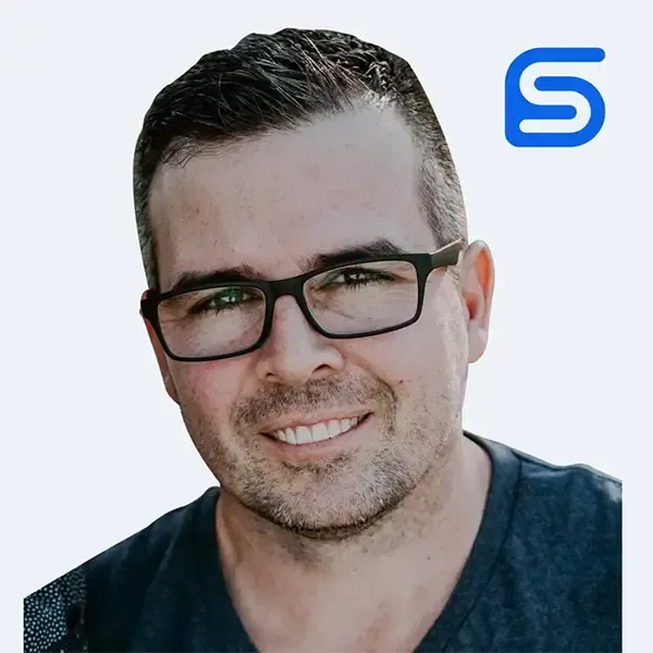 A man wearing glasses and a black shirt is smiling.