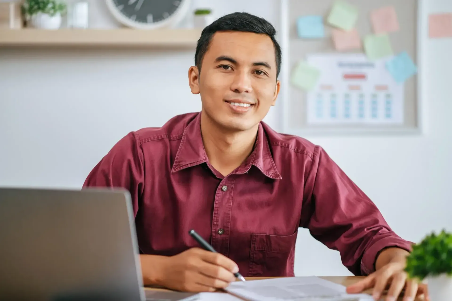 A woman wearing headphones is sitting at a desk using a laptop computer.
