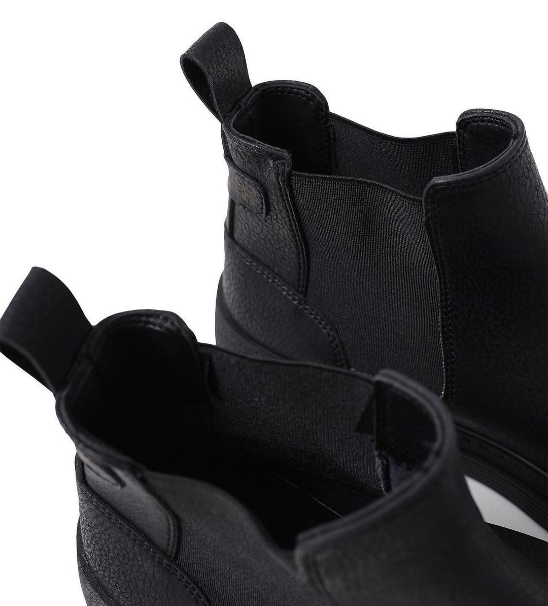 Un primer plano de un par de botas negras sobre un fondo blanco.