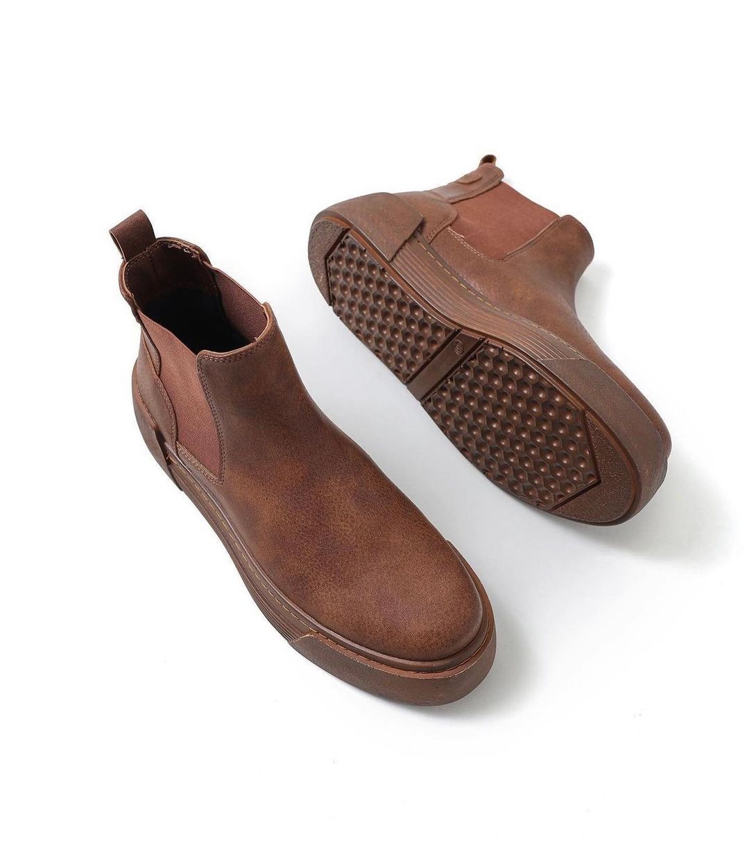 Un par de botas marrones sobre un fondo blanco.